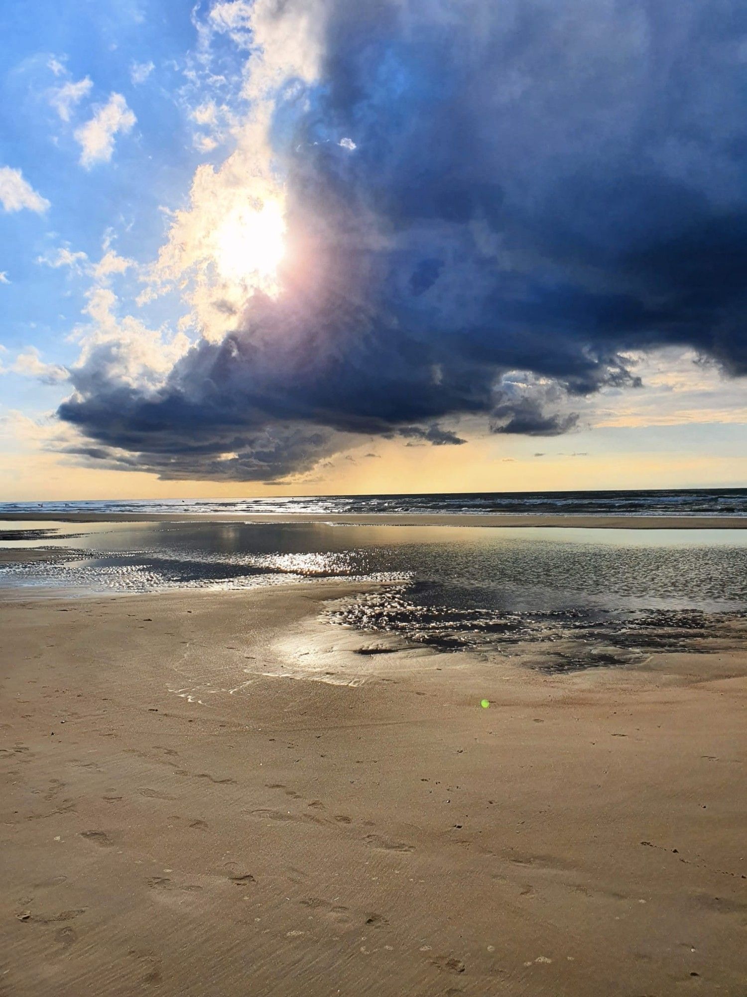 Strand bei Ebbe
darüber die Sonne, hinter Wolken versteckt