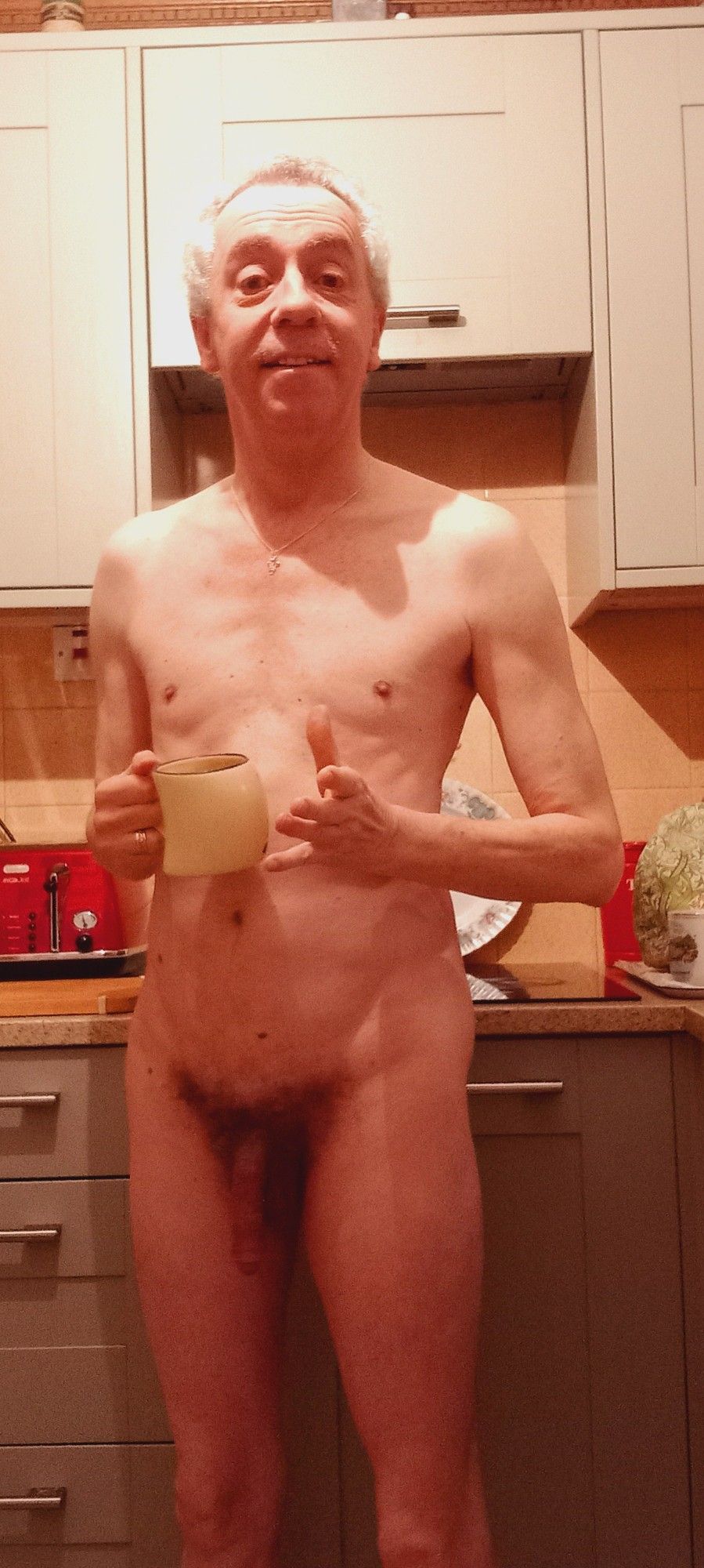 A nudist in the kitchen with a cup of tea