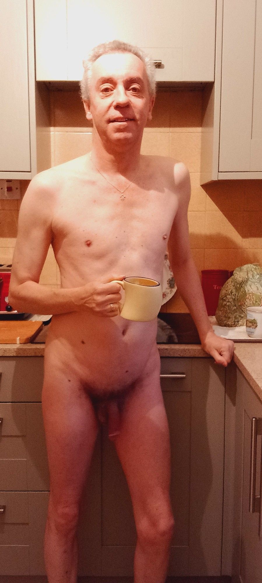 A nudist in the kitchen with a cup of tea