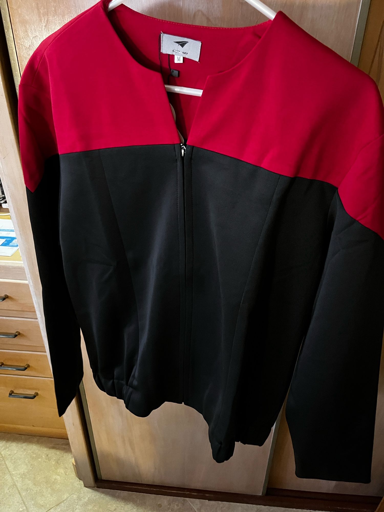 A Starfleet command uniform, circa 2273, hangs on a hanger.