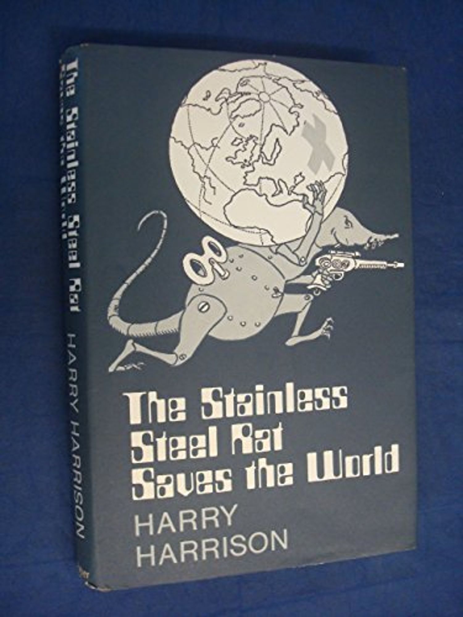 An old cover for 'The Stainless Steel Rat Saves the World' by Harry Harrison. On a dark grey background a grey cartoon robotic rat with a wind-up key in its side and a laser pistol in one hand carries a glob on it's back as it runs. The globe has a large cross over Russia. The title is written in a now retro computer / cyber font.