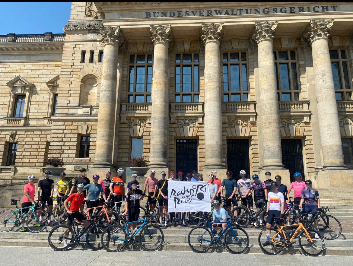 Eine gruppe radfahrende vor dem bundesverwaltungsgericht in leipzig
In der mitte halten sie ein banner mit „radsport gegen rechts“