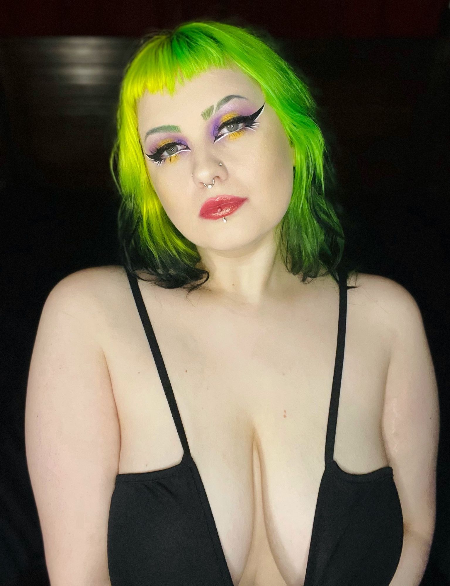 Pic of CiCi irl with non binary themed makeup and pulling their shirt down to show cleavage