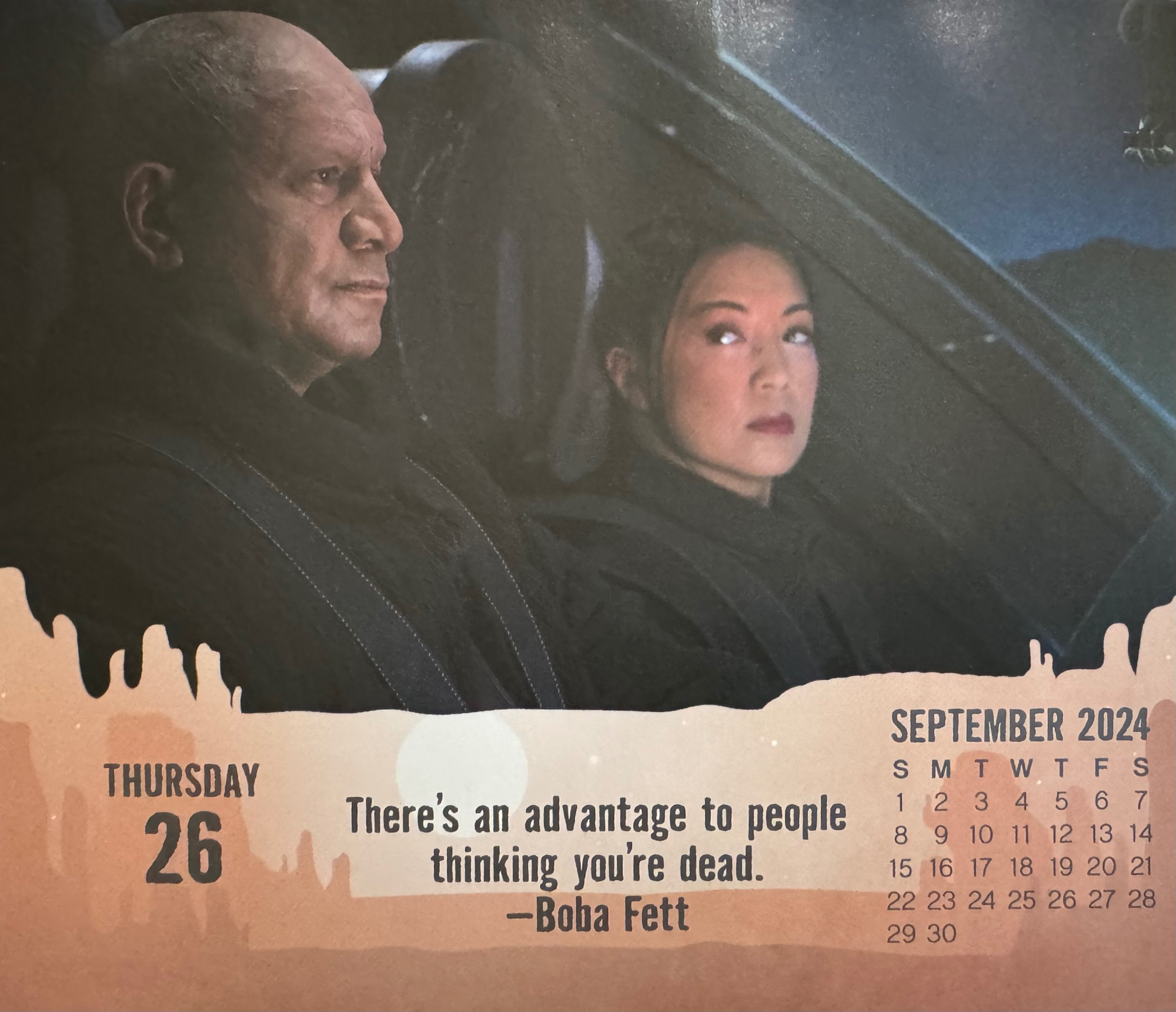 Boba Fett speaking to Fennec Shand on board the Firespray. Caption reads: There's an advantage to people thinking you're dead. Image from The Book of Boba Fett, Season 1, Episode 4, The Gathering Storm. Calendar by DateWorks.