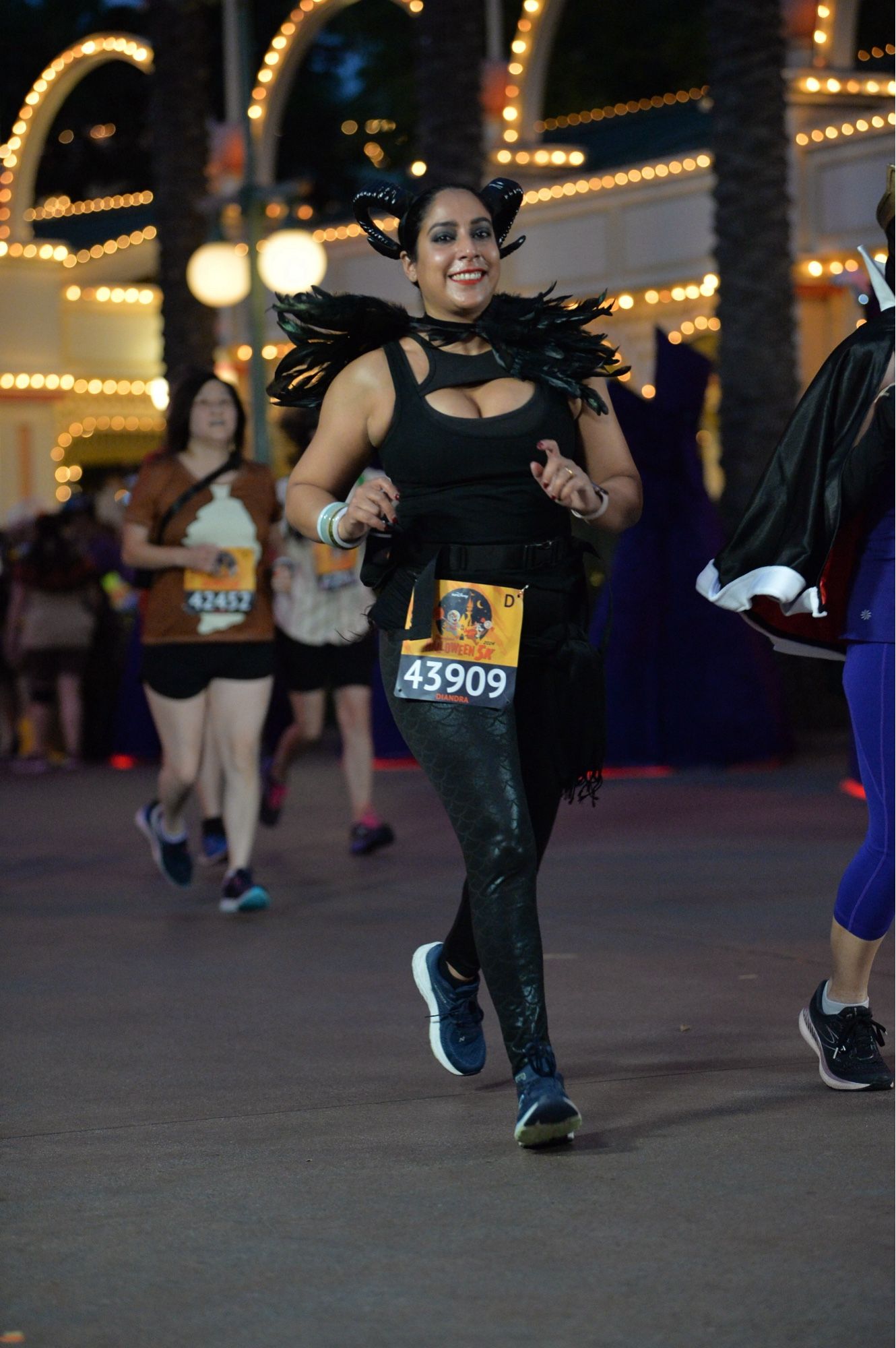 Diandra dressed for the Disneyland 5k as Malificent, she is wearing scale leggings, a feather caplet, and curved horns.