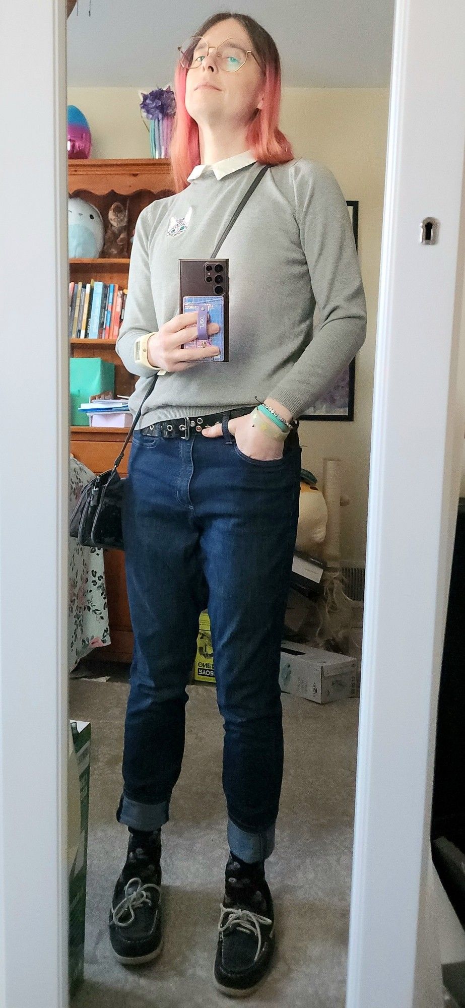 mirror selfie of me in a tight collared shirt with an embroidered kitten, a cuddlecore number of bracelets and an oversized watch, beaten up purse, a studded belt with stars on it, cuffed jeans, otter print socks and loafers