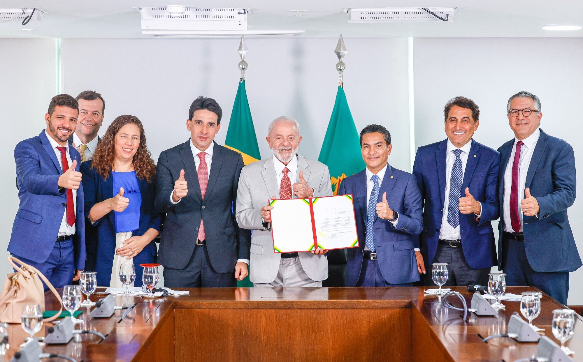 Presidente Lula ao lado de ministros, parlamentares e demais representantes do governo federal. Todos posam para foto segurando dois documentos assinados pelo presidente.