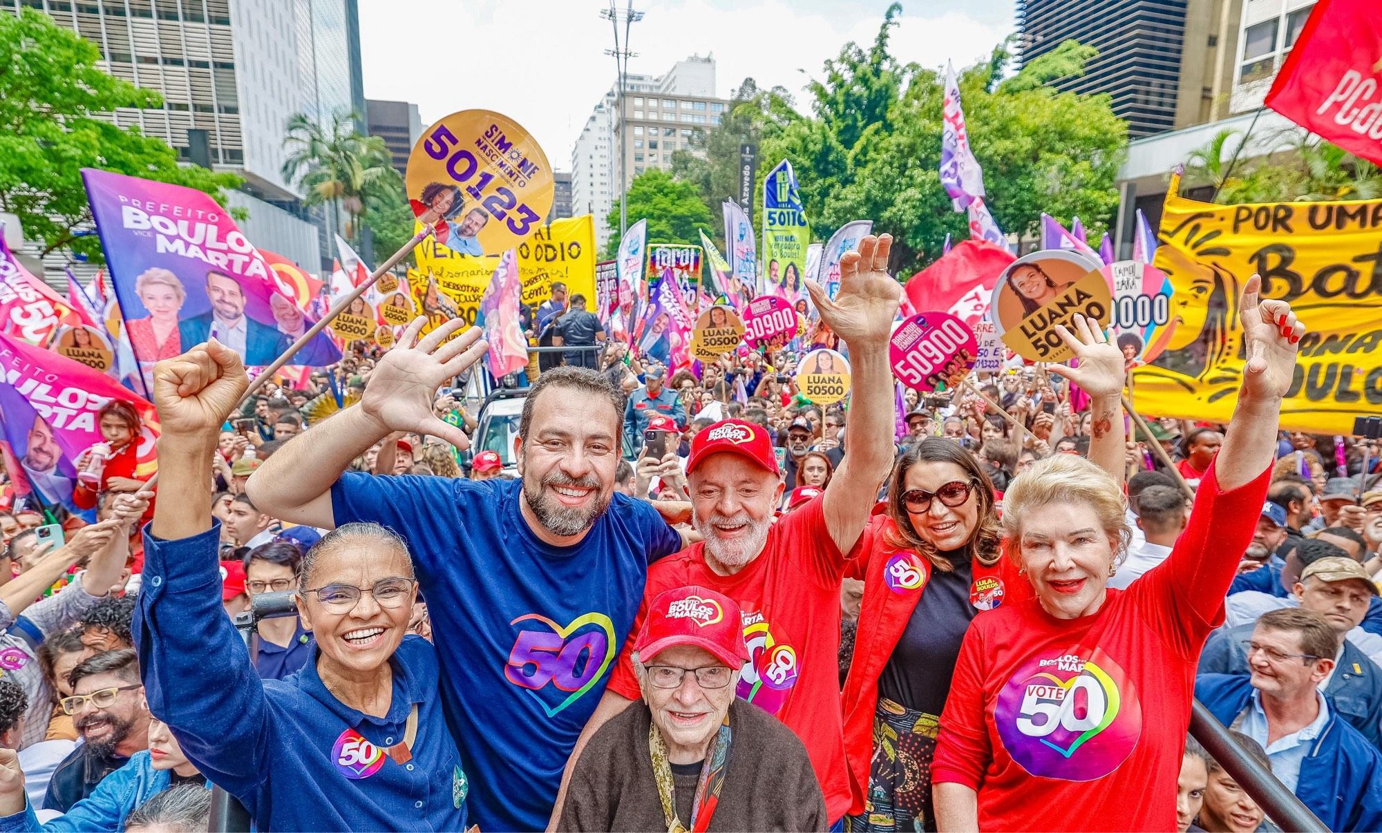 Lula e Boulos no centro da foto erguem os braços sorrindo, ao lado de Marina Silva, Luiza Erundina, Janja e Marta Suplicy