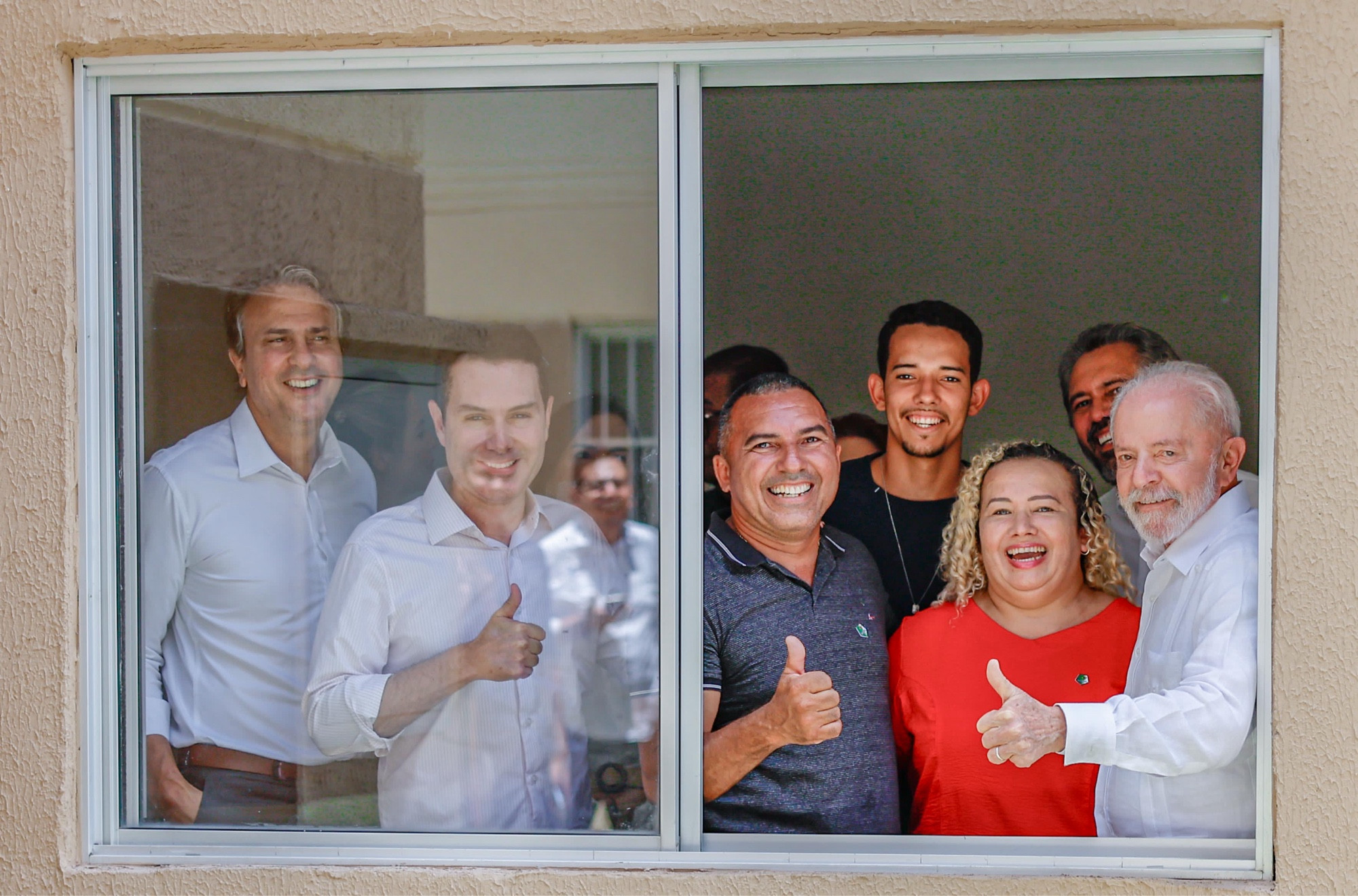 Na foto, o presidente Lula sorri ao lado de novos moradores do conjunto habitacional Cidade Jardim I Módulo IV, no Conjunto José Walter, em Fortaleza (CE). Ao lado deles, o ministro da Educação Camilo Santana e o ministro das Cidades, Jader Filho, e o governador do Ceará Elmano de Freitas. Todos posam para foto olhando para a janela, de dentro pra fora da casa.