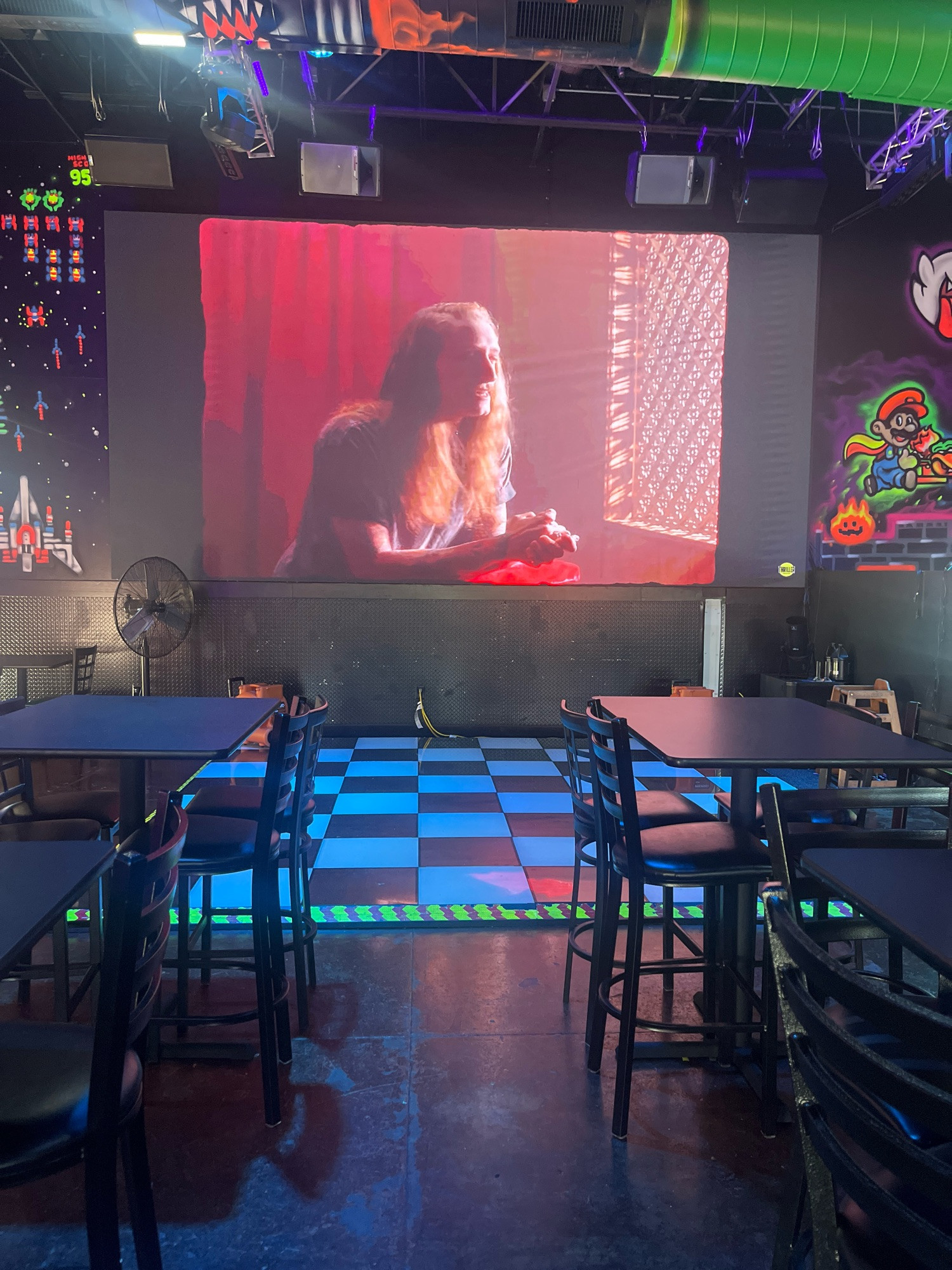 large video screen on the wall of a bar above a dance floor, showing the music video for Brag by The Home Team