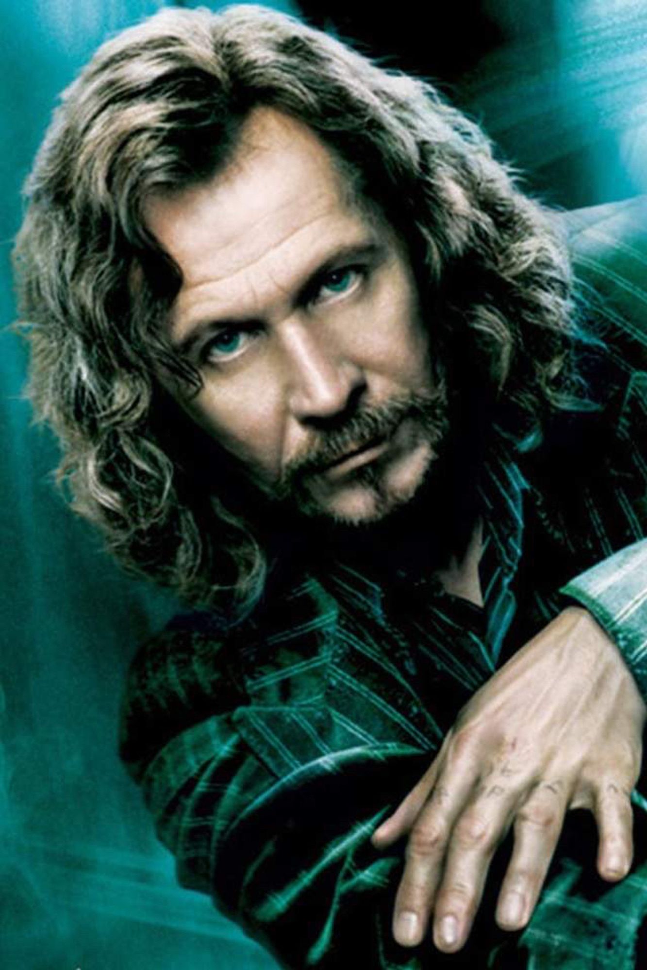 Gary Oldman as Sirius Black: wavy brown hair, goatee, pinstripe jacket and intense stare