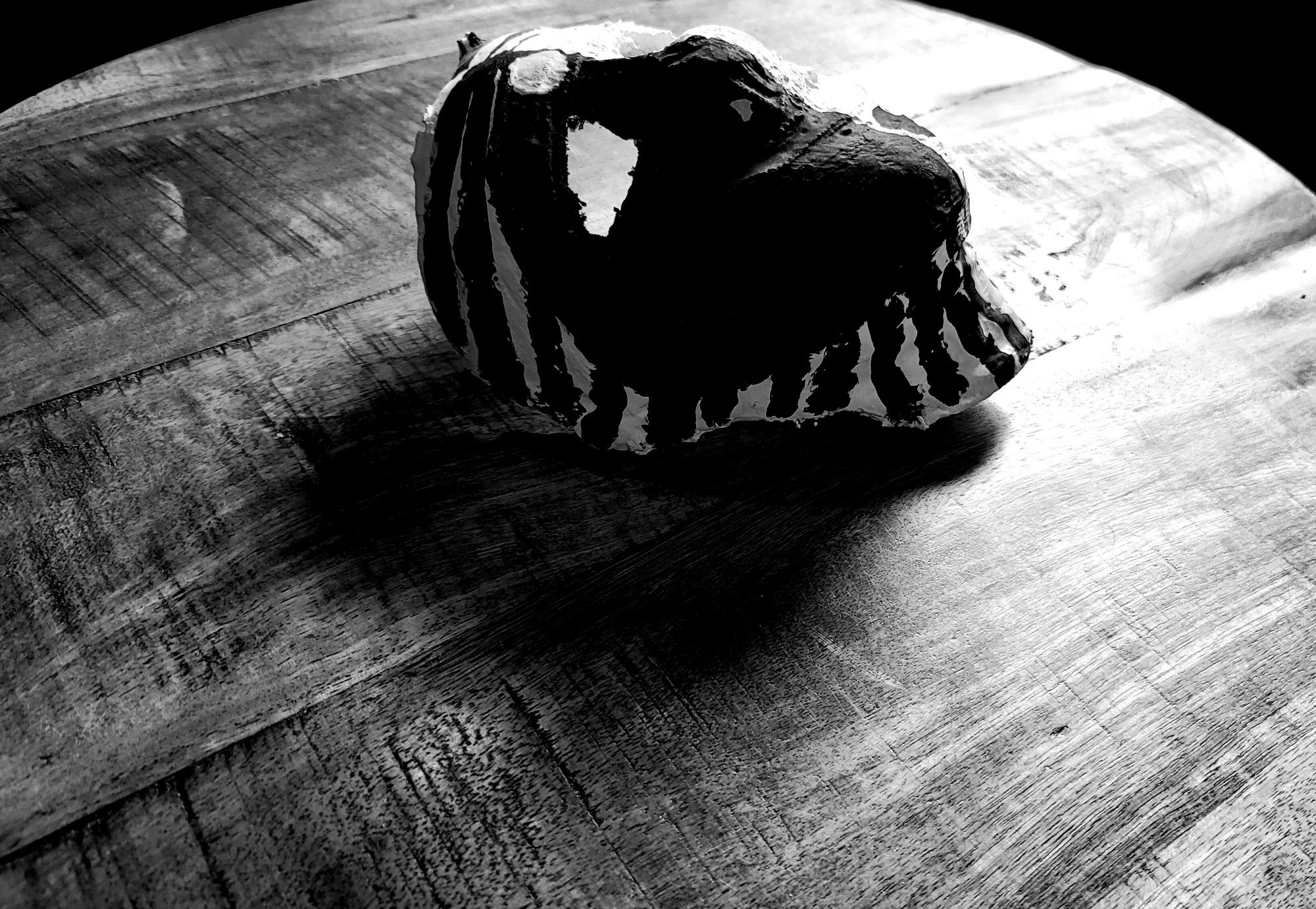 A plaster, black and white mask on a java wood table, taken in March of 2023.