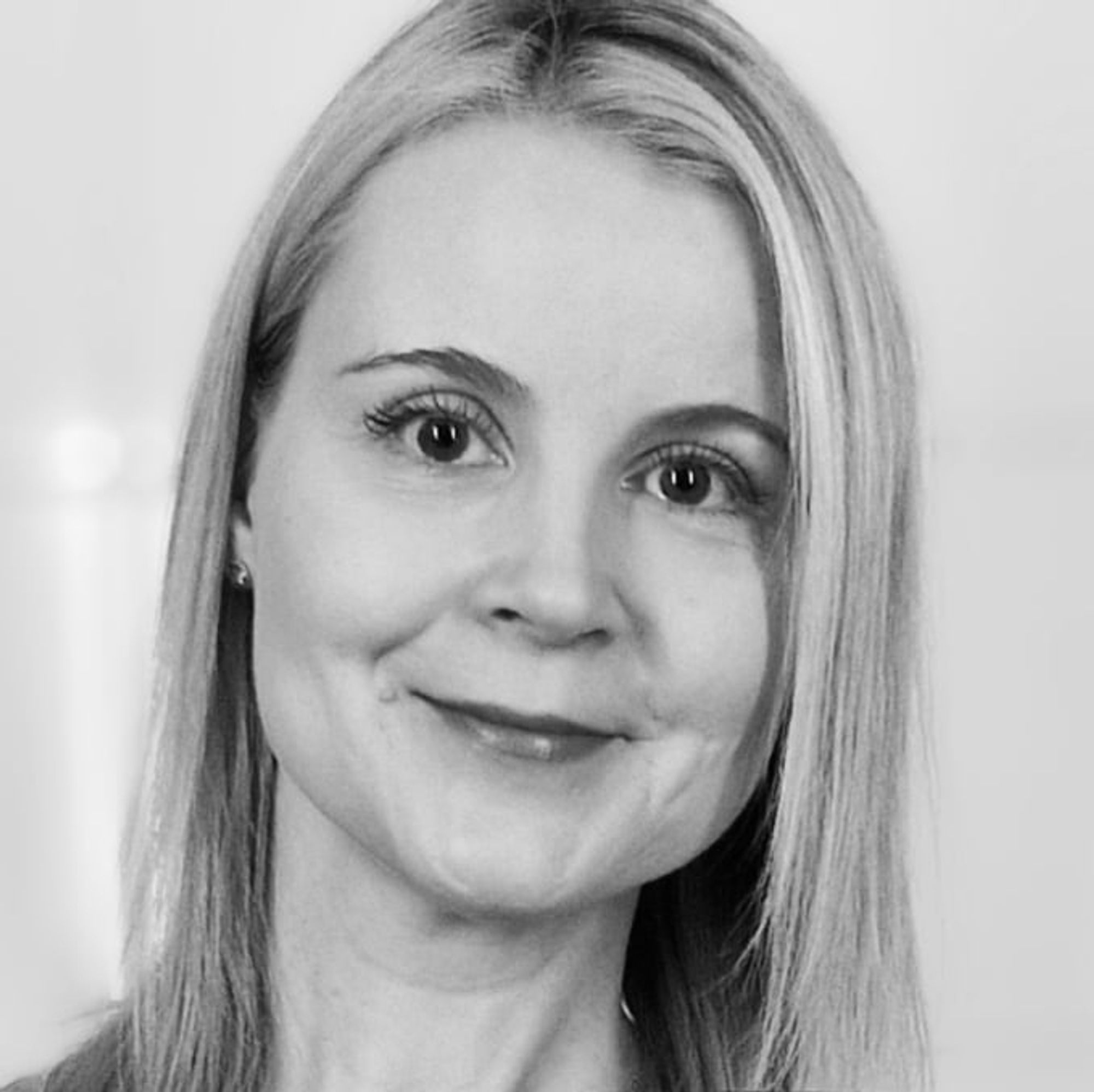 A black and white close-up of my head. I have straight, blonde, over shoulder length hair and I'm smiling.