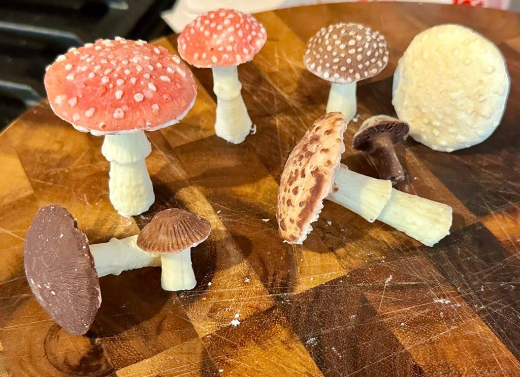 Several chocolate mushrooms set on a wooden cutting board