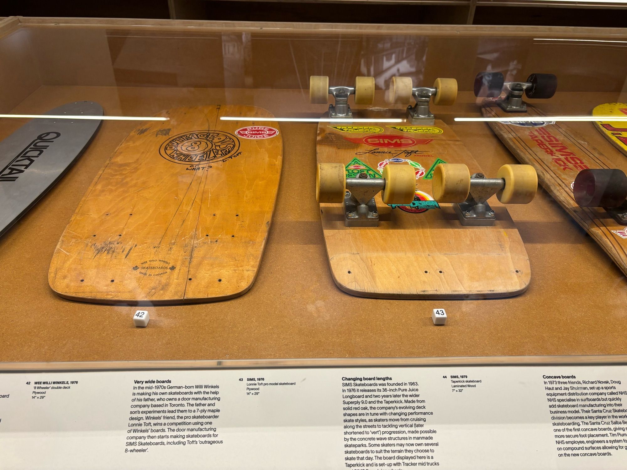 Two extra wide skate decks in the Skateboard exhibition labelled “The Outrageous Eight Wheeler” with four sets of trucks and eight wheels