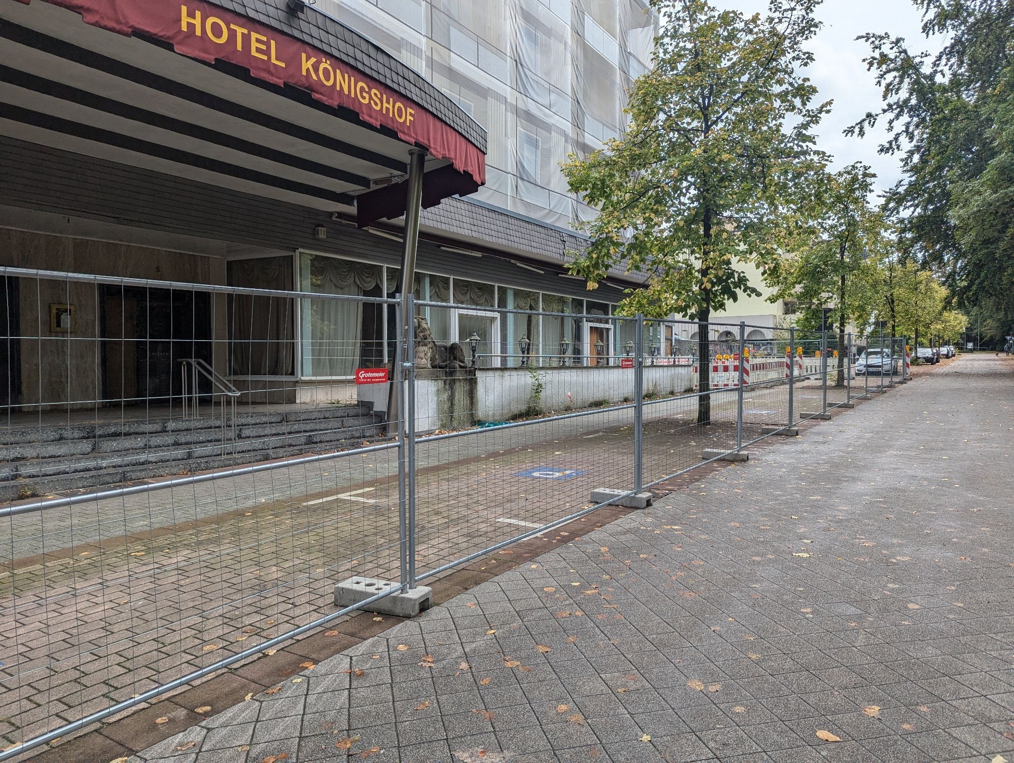 Ein ehemals mondänes Hotel mit einer hinter Planen verstecken Fassade und einem Bauzaun davor.