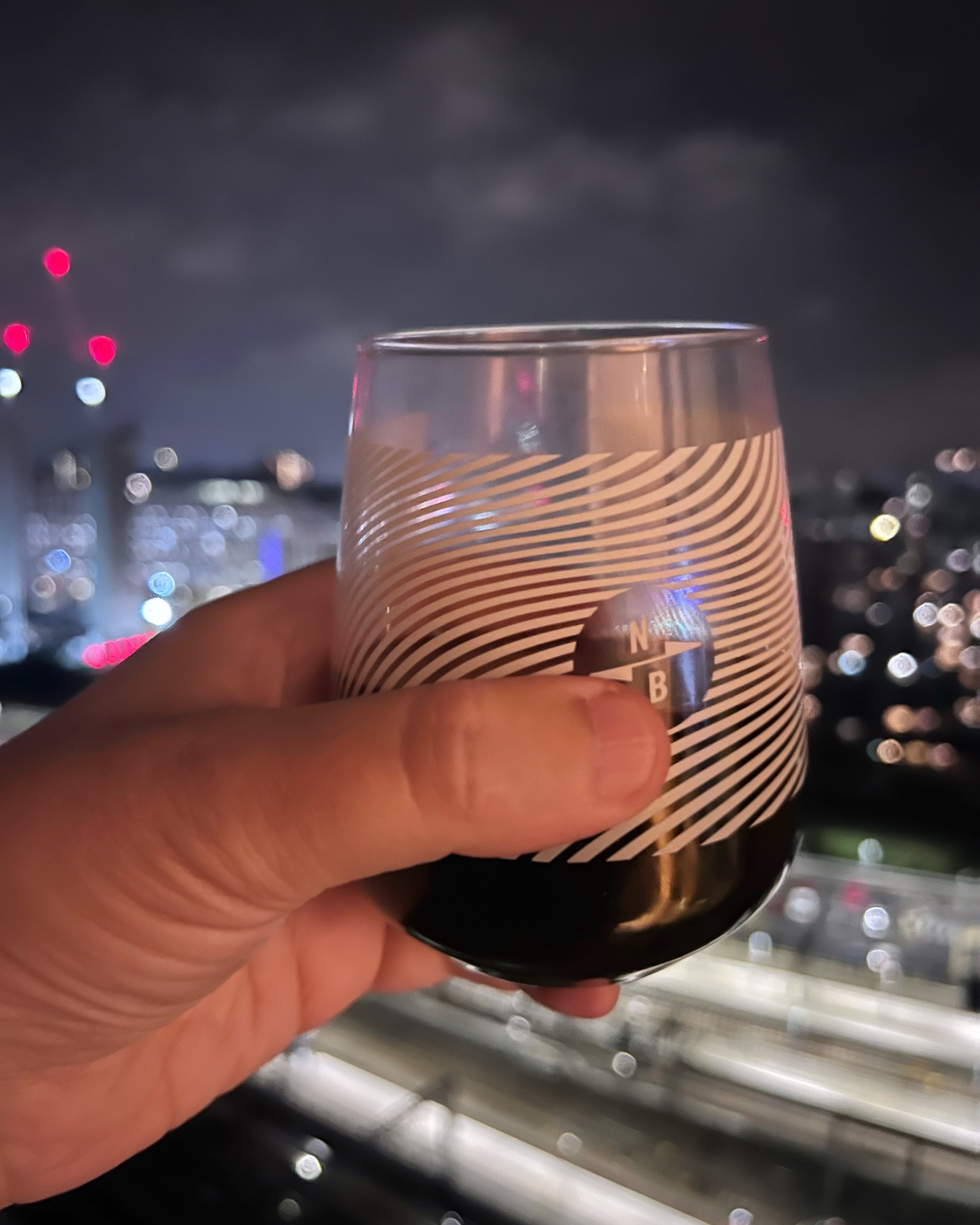 Glass of red held in my left hand in front of the night sky in the centre of Leeds