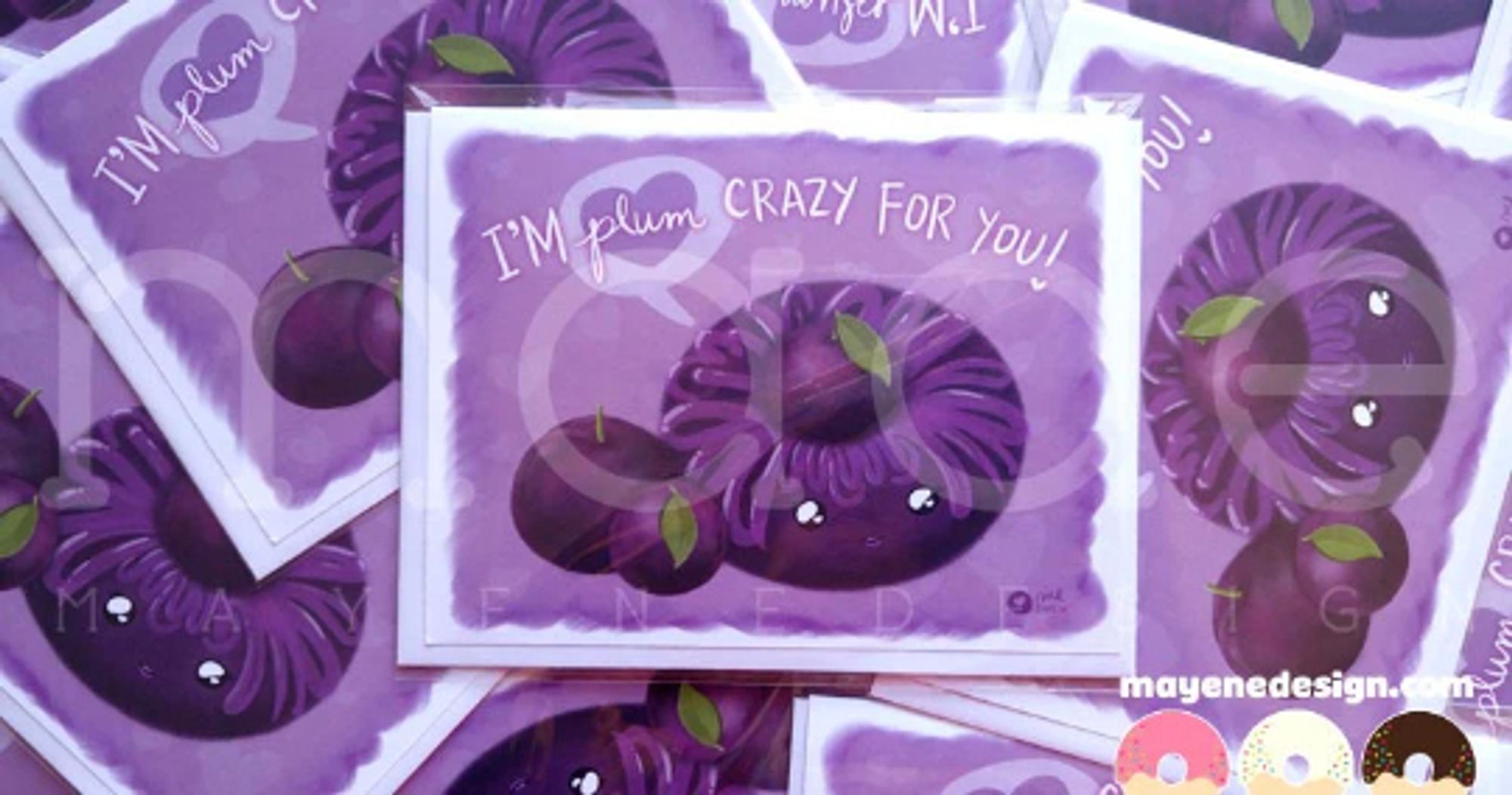 A purple card showing a purple donut with a happy face on it and purple glaze, surrounded by small juicy plums. The card says: "I'm plum crazy for you!"