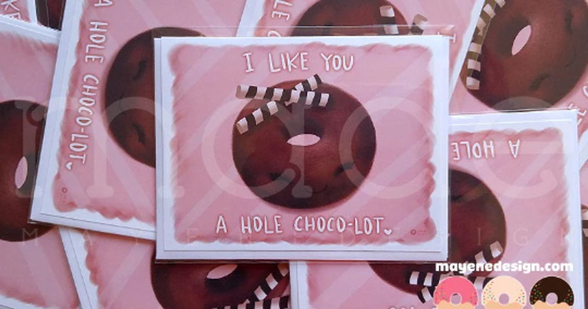 A pink card showing an illustrations of a chocolate cake donut with a happy face and some chocolate striped sticks as toppings. The card says: "I like you a hole choco-lot."