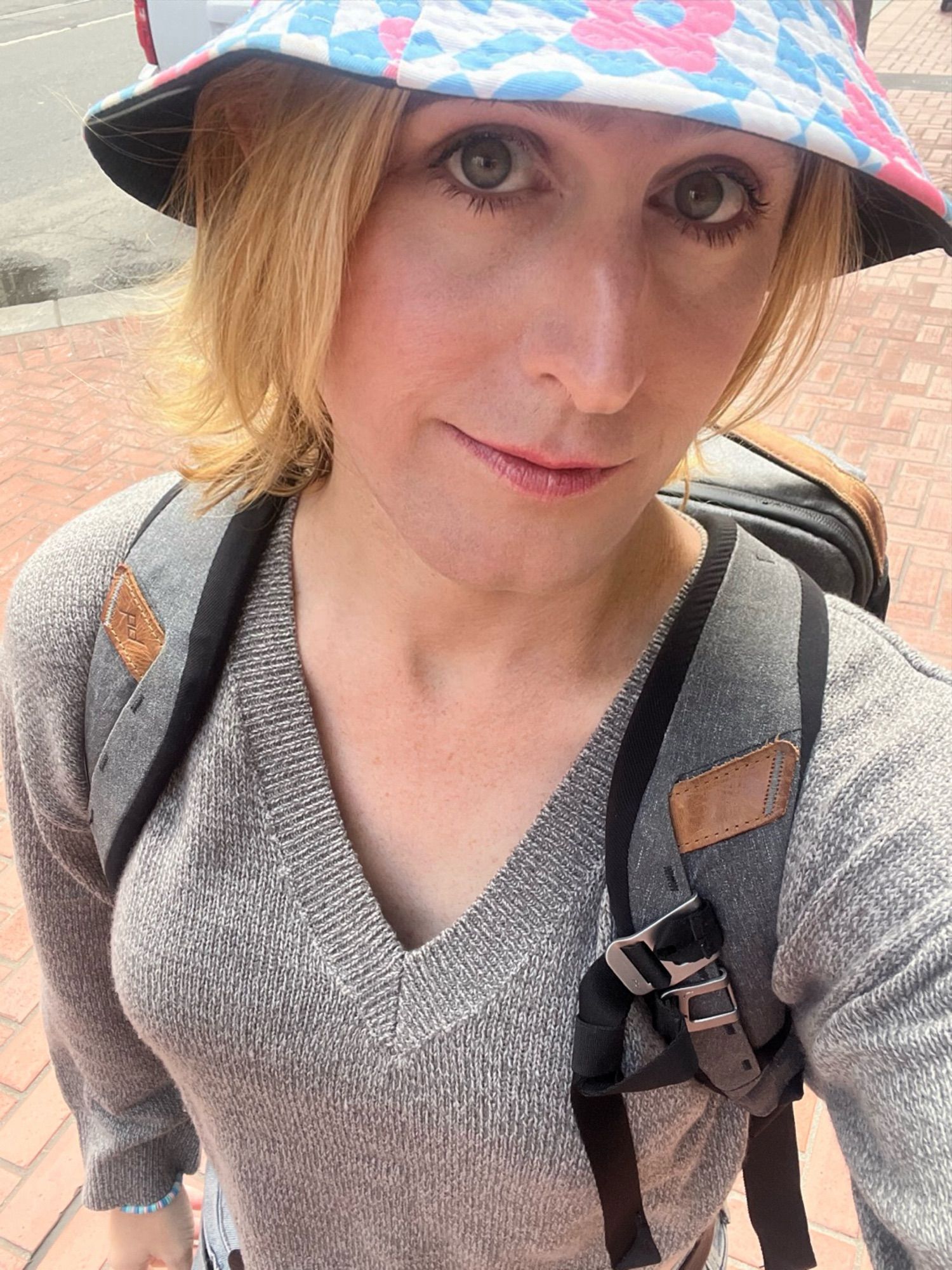 a white woman in a grey crop sweater wearing a backpack and a trans color flower bucket hat.

she's en route to her pre-op appointment in downtown san francisco at the time and she's smiling. she's genuinely happy