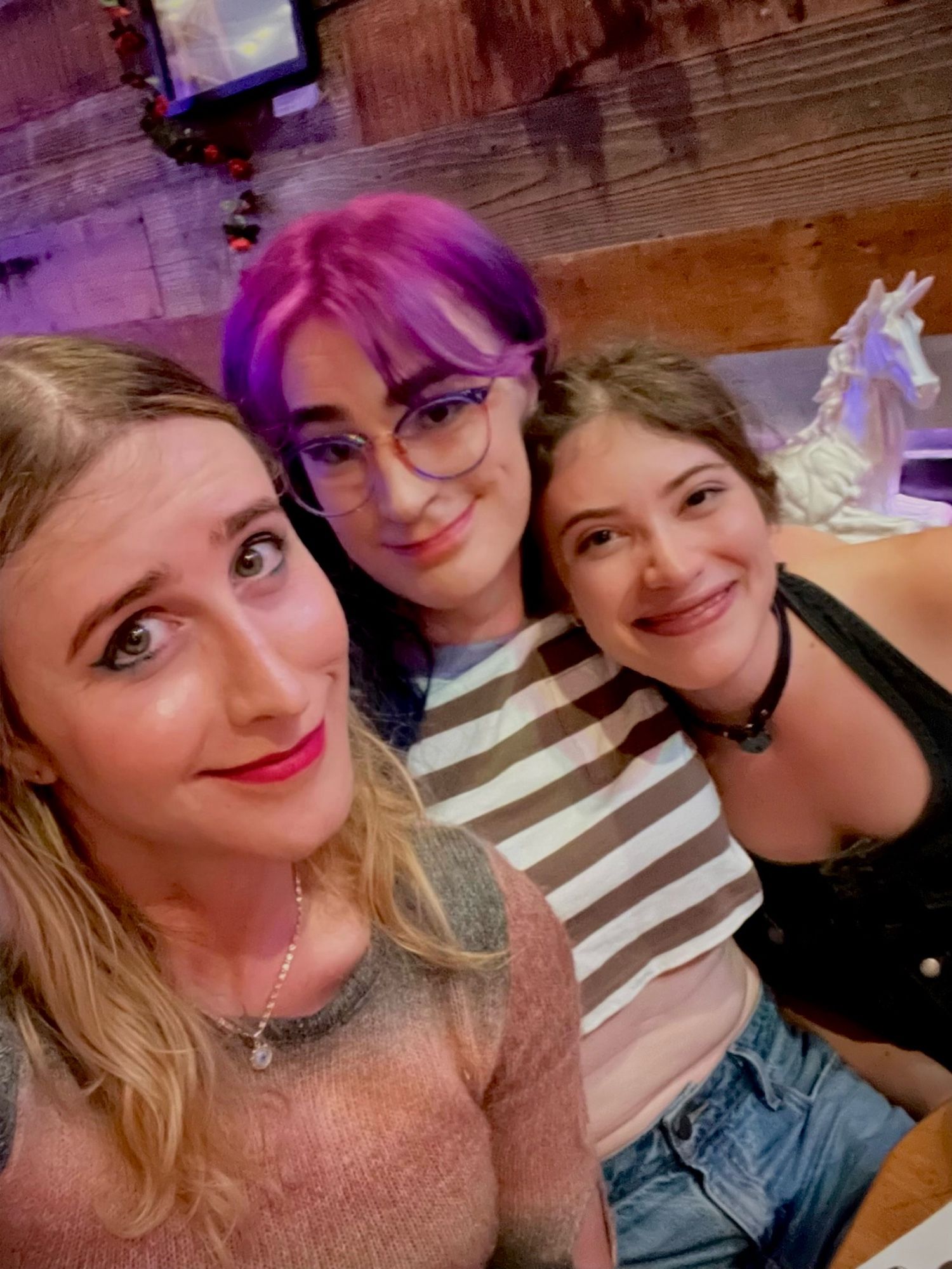 a selfie of Emma, Becs, and Neve at Emmy's Spaghetti Shack (yes, that's the name lol) in San Francisco 

they're smiling and looking gorgeous. 

Emma has a crop sweater and evil eye necklace, Becs is in a striped crop and Neve is in overalls and a heart collar