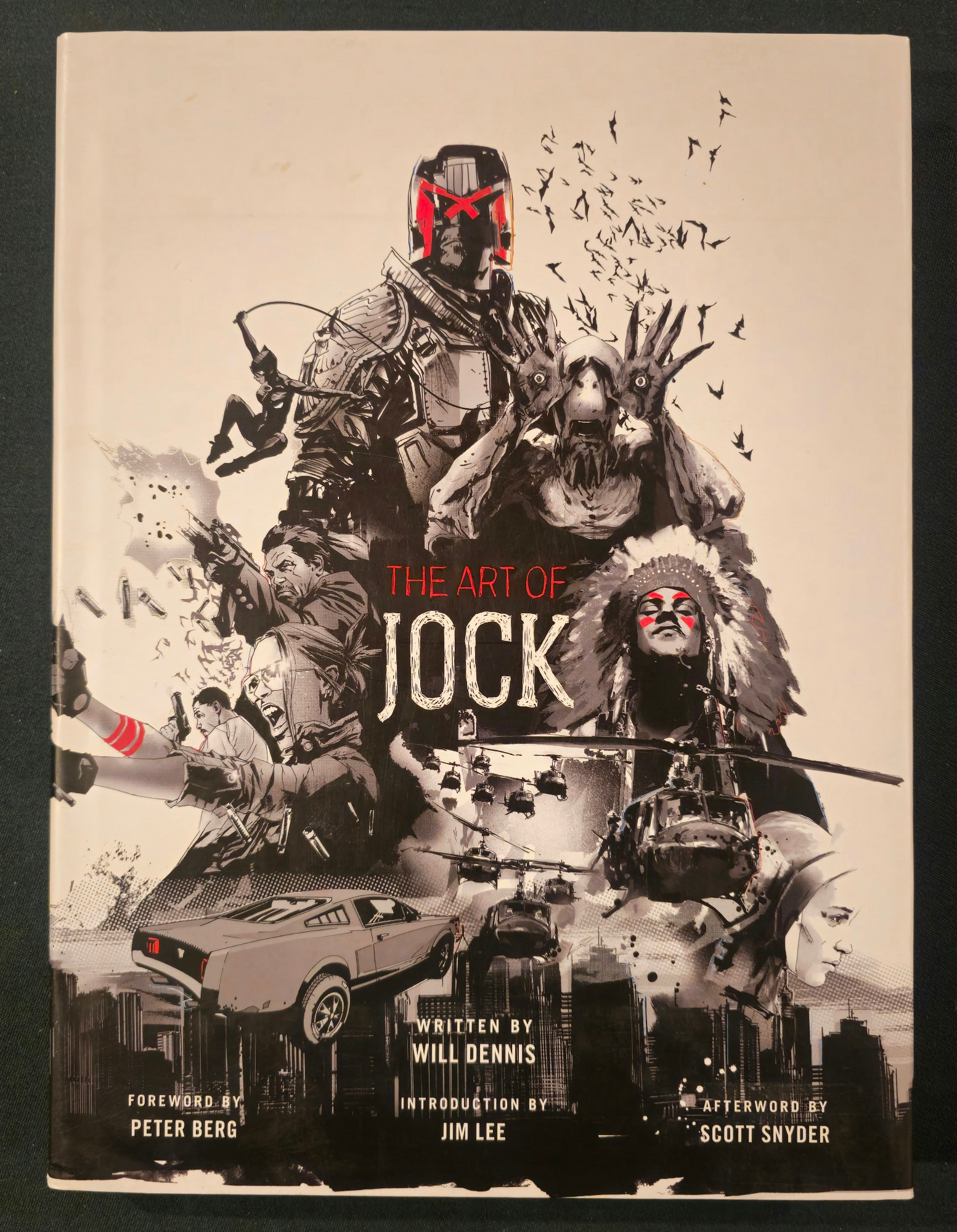 The cover to The Art of Jock. It features a sampling of his art including Judge Dredd, the creepy guy from Pan's Labyrinth, the main guy from Scalped, the Apocalypse Now helicopters, Ava from Ex Machina, Gotham City, a car from The Losers, The Losers, and Catwoman.