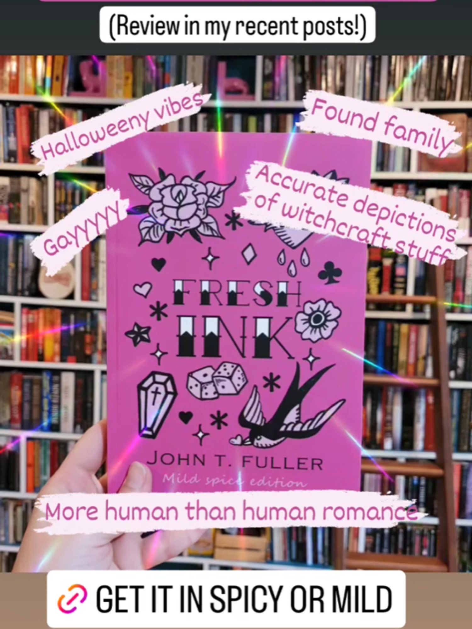 Image shows photo of the front cover of Fresh Ink (mild spice edition) which is pink with traditional tattoo font and illustrations of traditional tattoo flash in black. The book is being held in front of a full wall bookshelf. Text says 'review in my recent posts! Halloweeny vibes, found family, gayyyyy, accurate depictions of witchcraft stuff, more human than human romance, get it in spicy or mild'