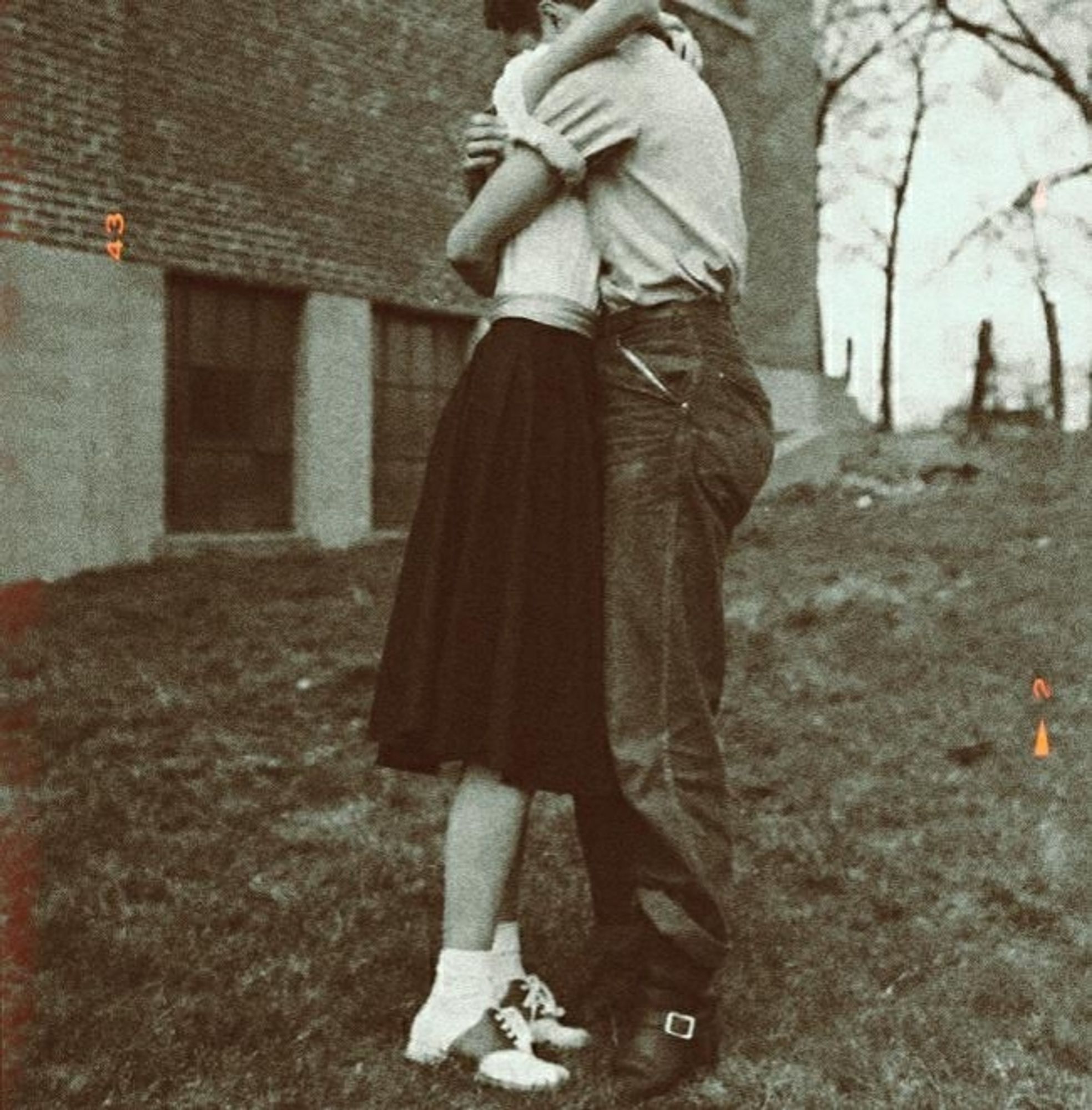 Imagem 4: foto em preto e branco de um casal com roupas típicas dos anos 40 abraçados em um jardim.