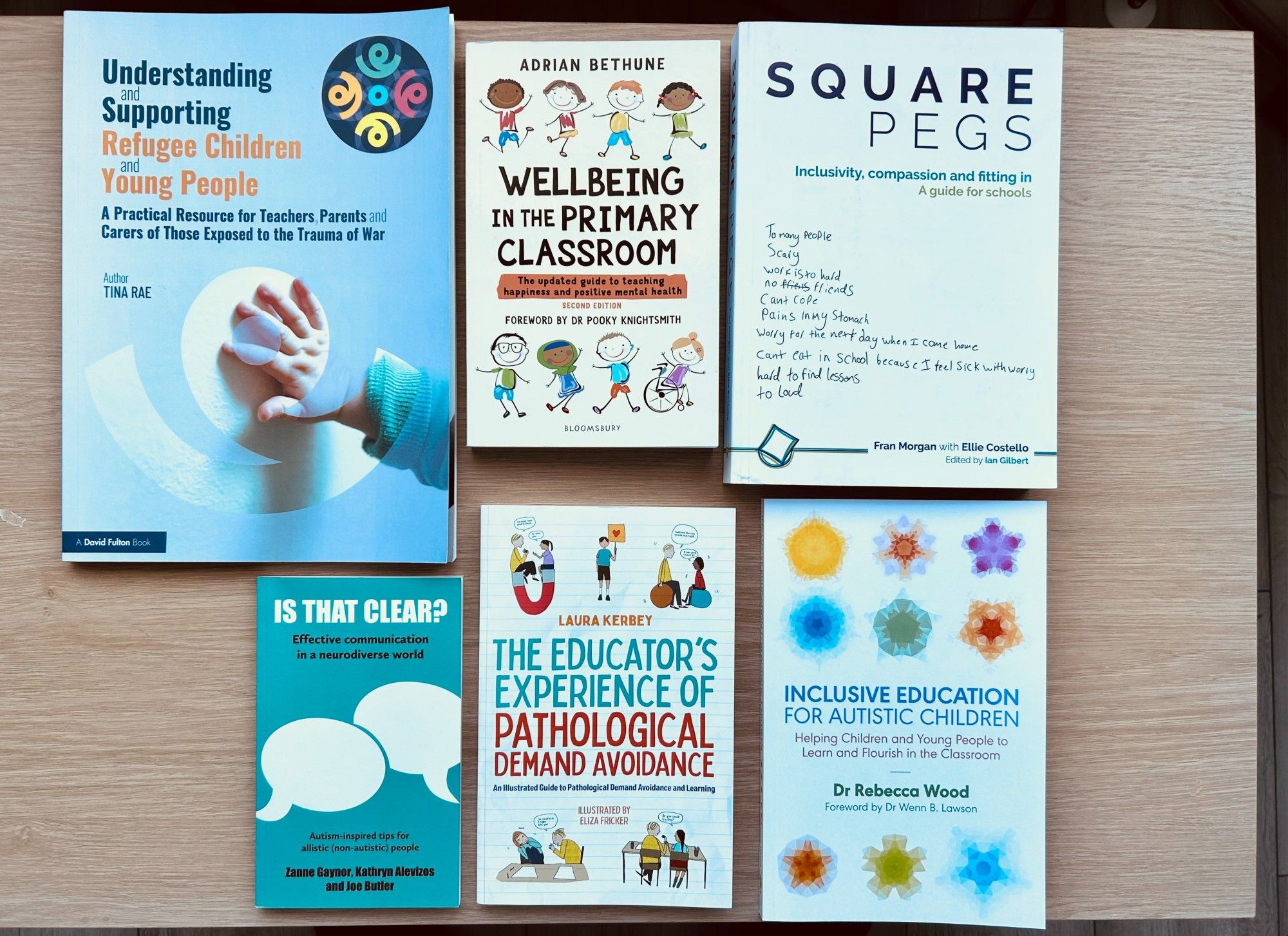 A photo of six books. The books are as follows: 

1. Square Pegs: Inclusivity, compassion, and fitting in. A guide for schools. Author: Fran Morgan with Ellie Costello. Edited by: Ian Gilbert.

2. Is that clear? Effective communication in a neurodiverse world.
Authors: Zanne Gaynor, Kathryn Alevizos, and Joe Butler.

3. The Educator’s Experience of Pathological Demand Avoidance.
Author: Laura Kerbey. Illustrator: Eliza Fricker.

4. Understanding & Supporting Refugee Children & Young People. A practical resource for teachers, parents, and carers of those exposed to the trauma of war. Author: Dr Tina Rae.

5. Wellbeing in the Primary Classroom. The updated guide to teaching happiness and positive mental health. Author: Adrian Bethune.

6. Inclusive Education for Autistic Children. Helping children and young people to learn and flourish in the classroom. Author: Dr Rebecca Wood.