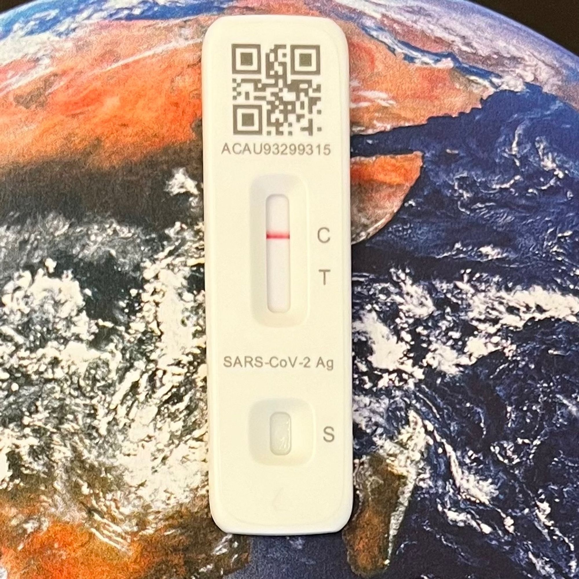 A COVID-19 test with a negative result against a background of the Earth from space.