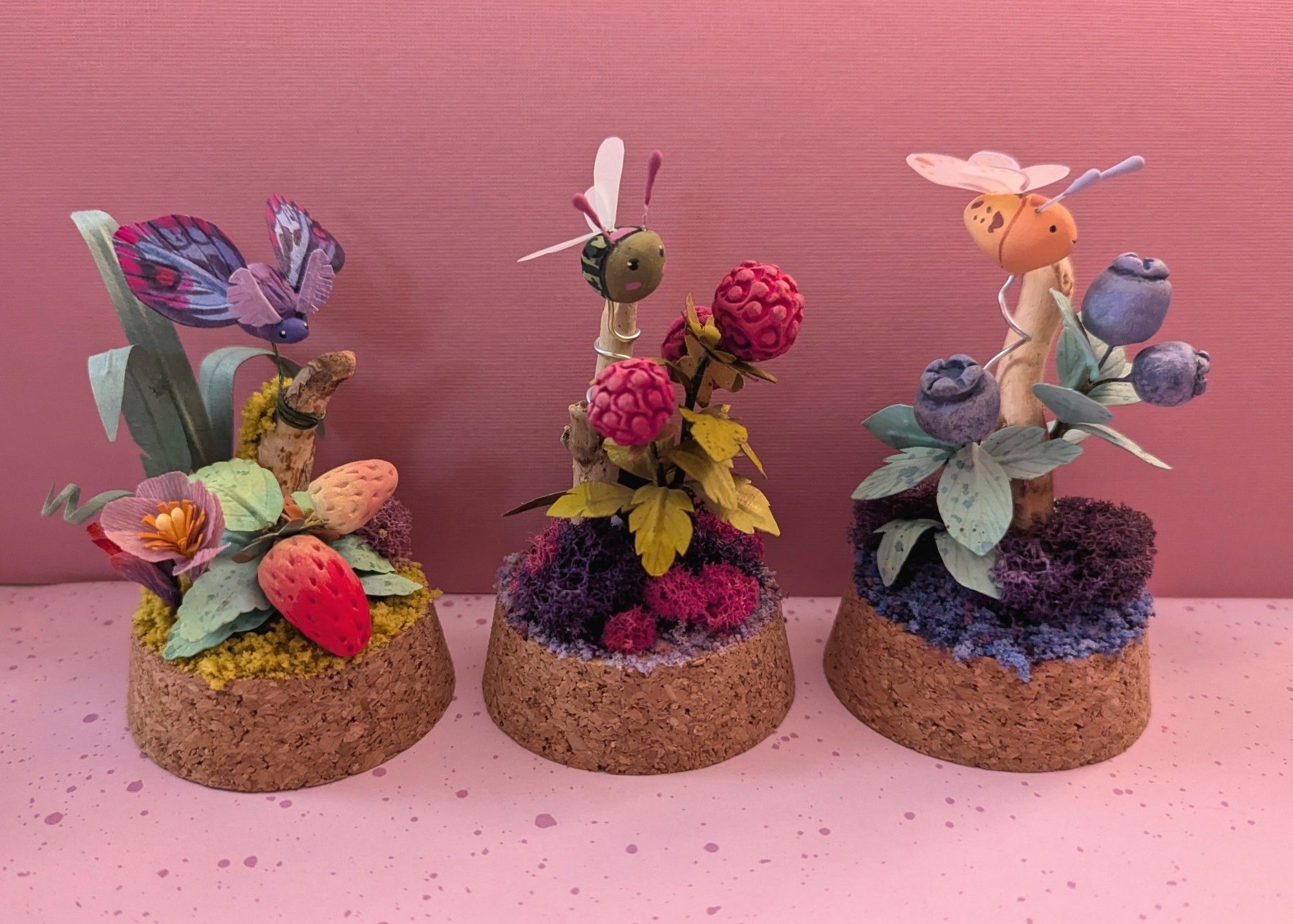 Sculptures with flying insects and berry plants.