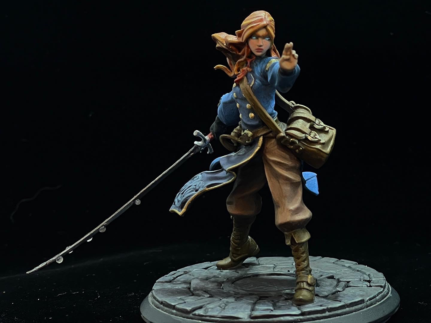 75mm scale miniature of Shallan Davar from the book series The Stormlight archive.
She’s facing front with one hand outstretched in a ready position, with a long thin blade held down to the side in her other hand.