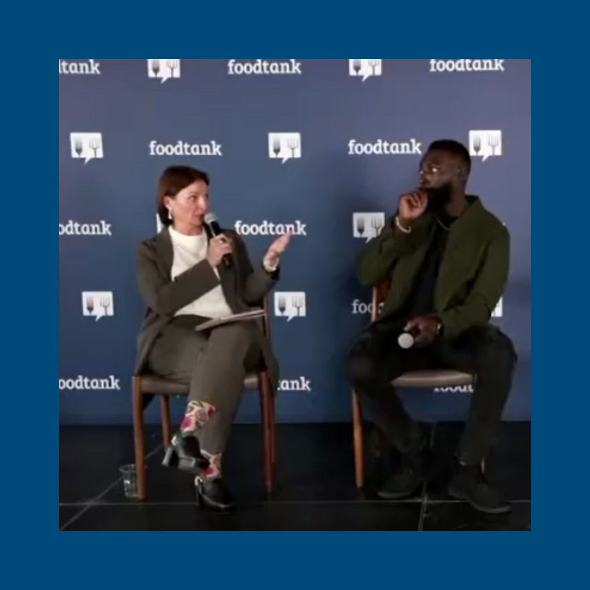 Anne McBride, seated left, holding a microphone and asking a question of Chef Eric Adjepong, seated right