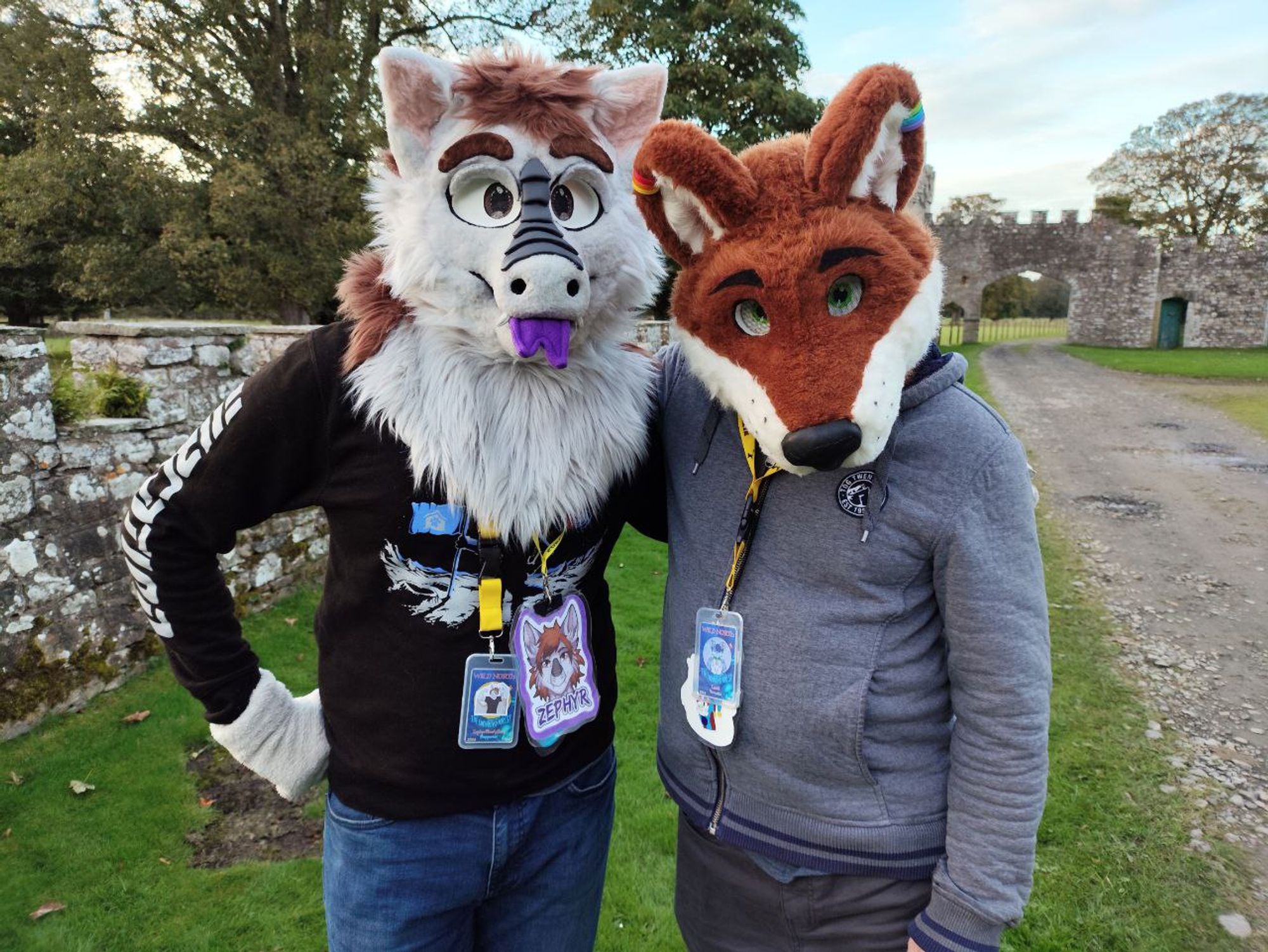 a photo of a fluffy dragon fursuiter and another fursuiter outside near a castle