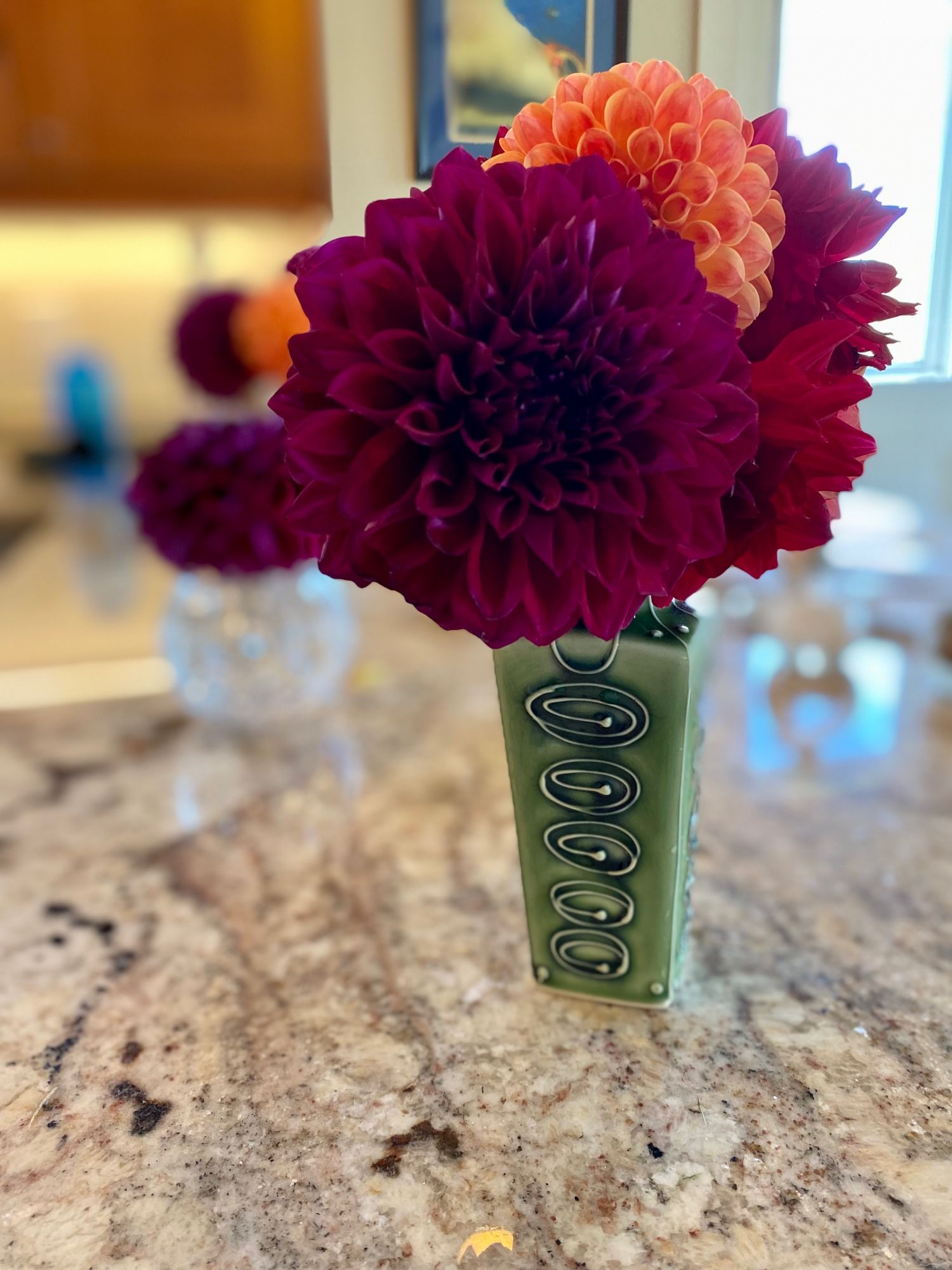 Brightly colored dahlias in a green vase.