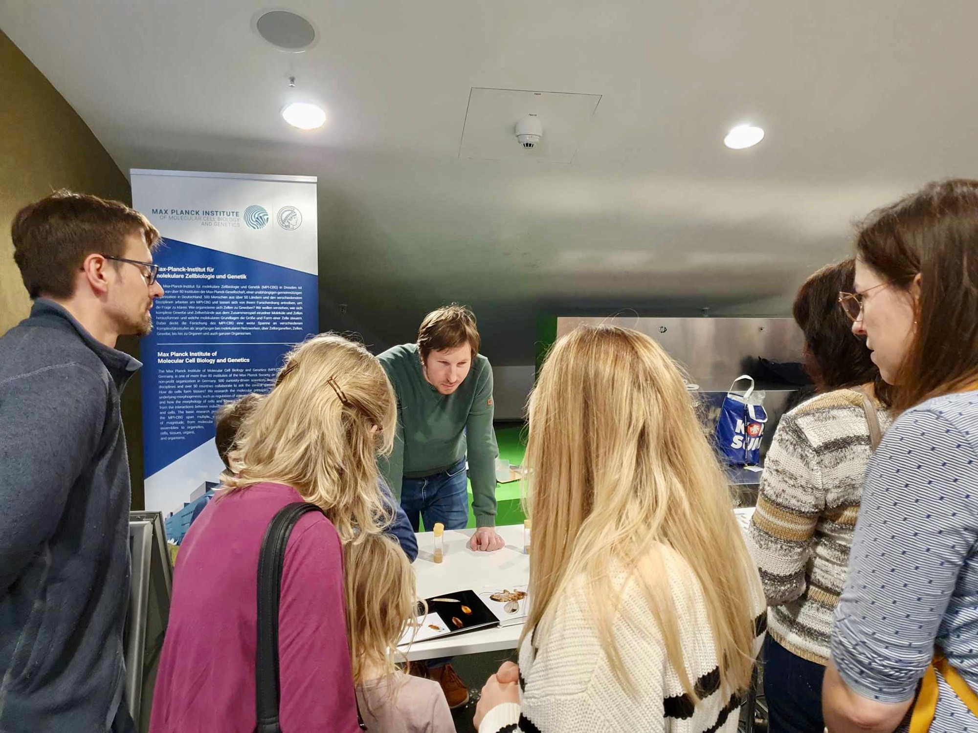 One researcher at a hands on science station with visitors.