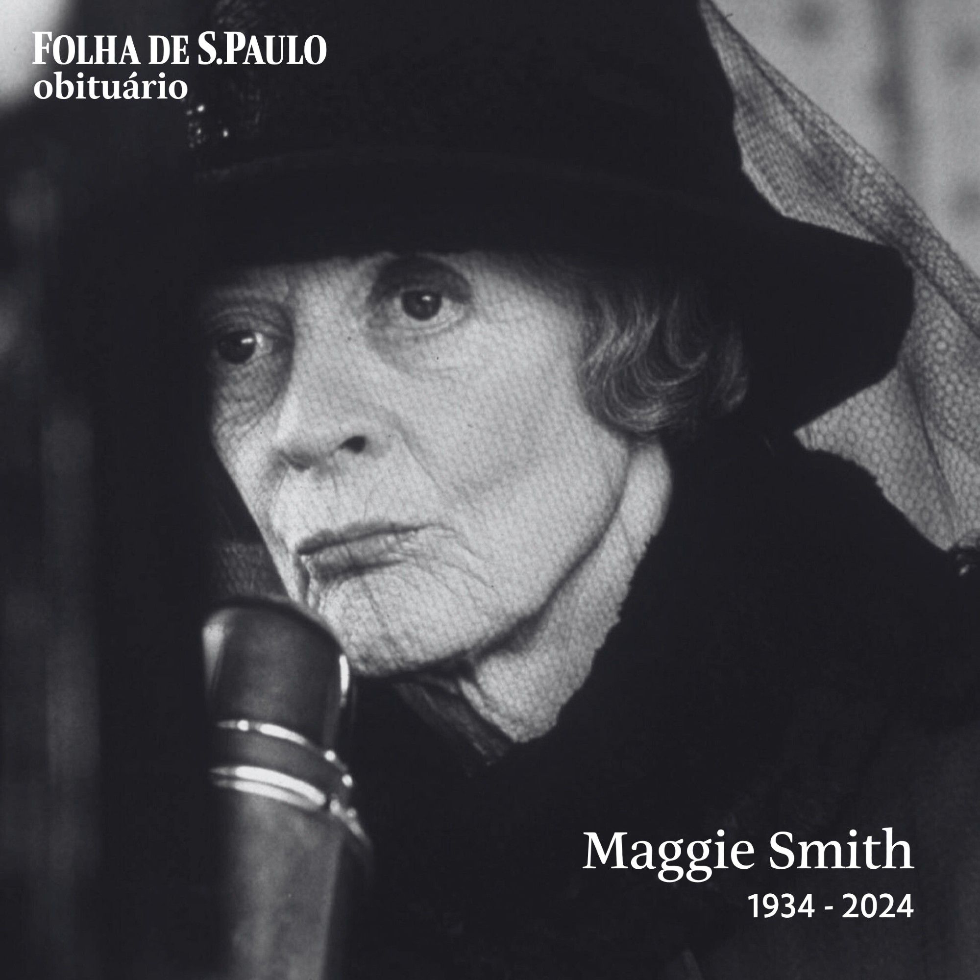 #PraTodosVerem: Fotografia em preto e branco é retrato de Maggie Smith em cena do filme "Gosford Park". Ela é uma mulher branca com cabelos lisos e curtos na altura das orelhas. Usa casaco, chapéu e véu pretos, fala em um microfone. Sobre a imagem há seu ano de nascimento (1934) e morte (2024).