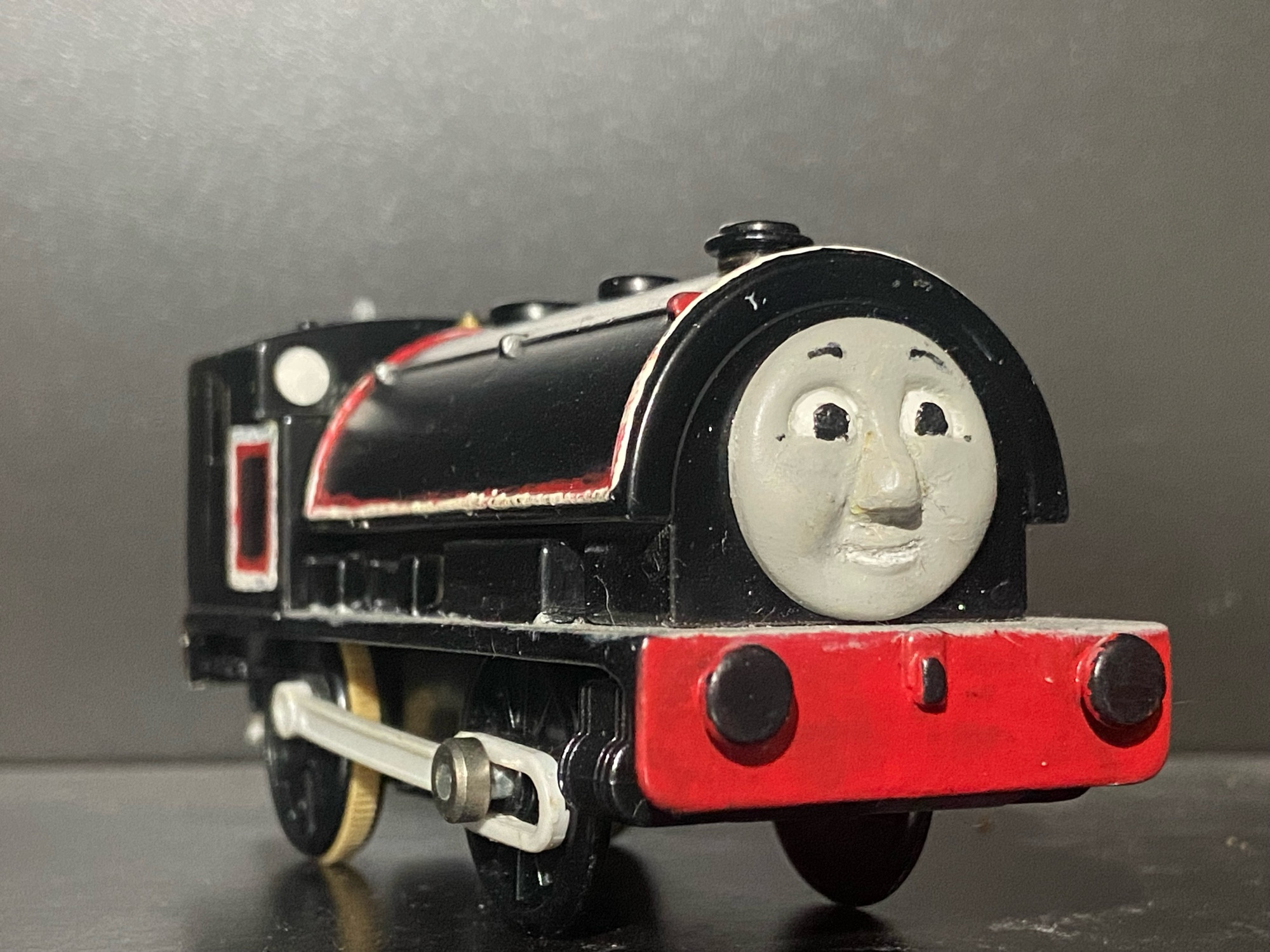 Side profile of Jinty, she has two tone white and red stripes across her saddle tank and bunker. There are white portholes on the front of her cab and she has a light grey footplate.