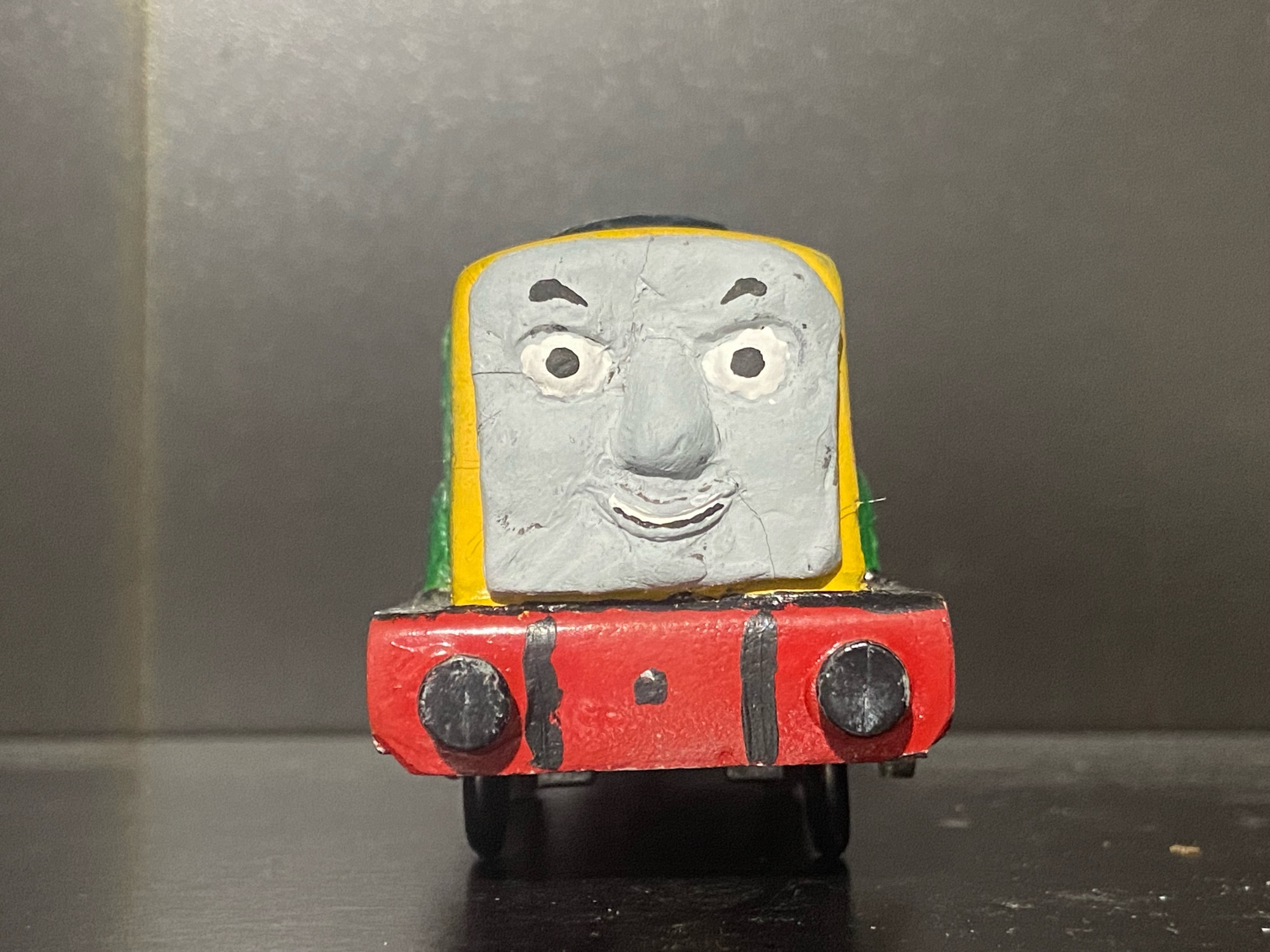 Front view of Derek the Paxman Diesel from Thomas & Friends, he is painted green with yellow at his ends.

His big grey face covers most of the yellow end at this side.