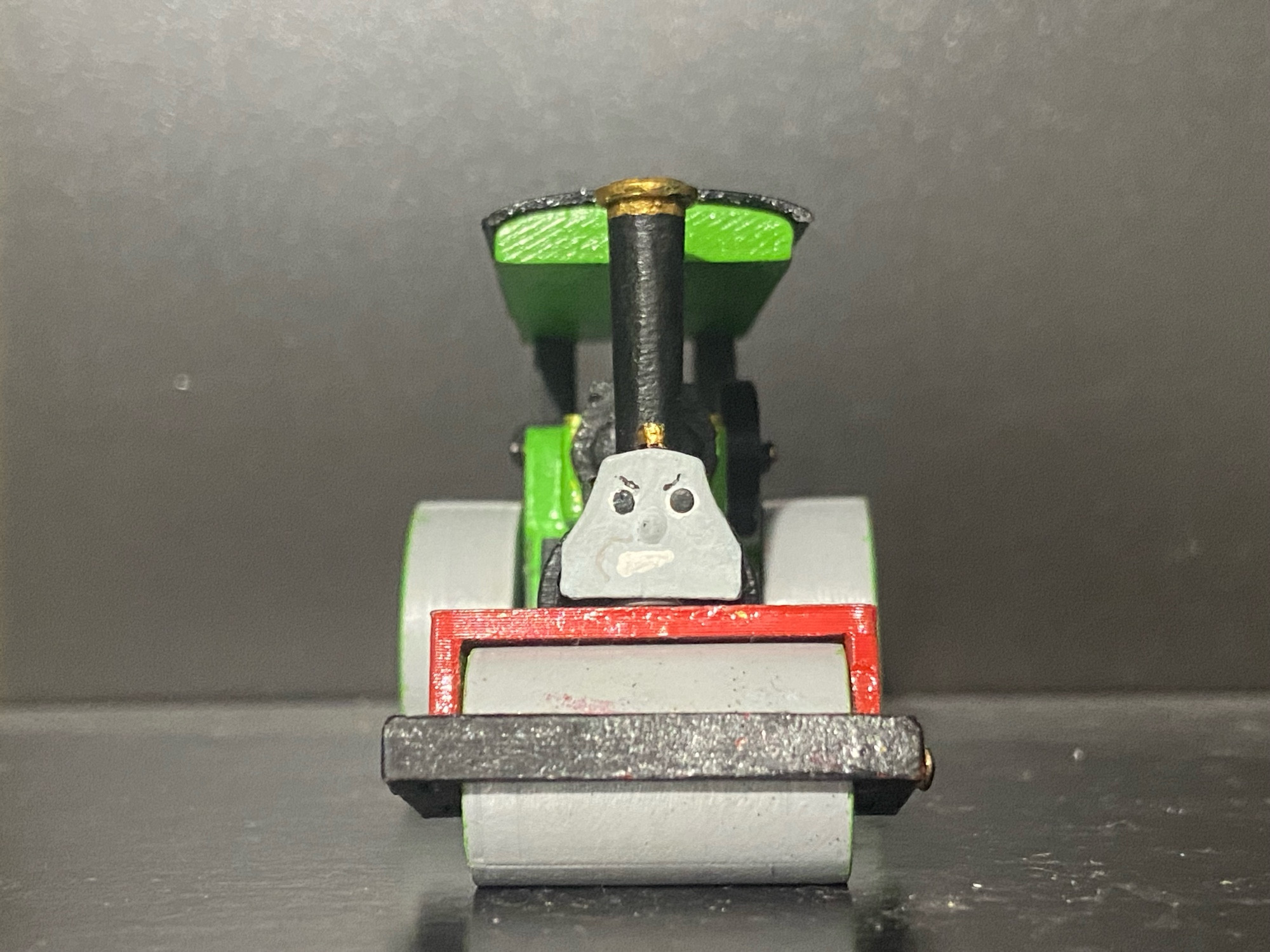 A 3d printed toy of George the Steam Roller from Thomas and Friends.

He is painted green primarily but does have gold, grey, red, and black accents.