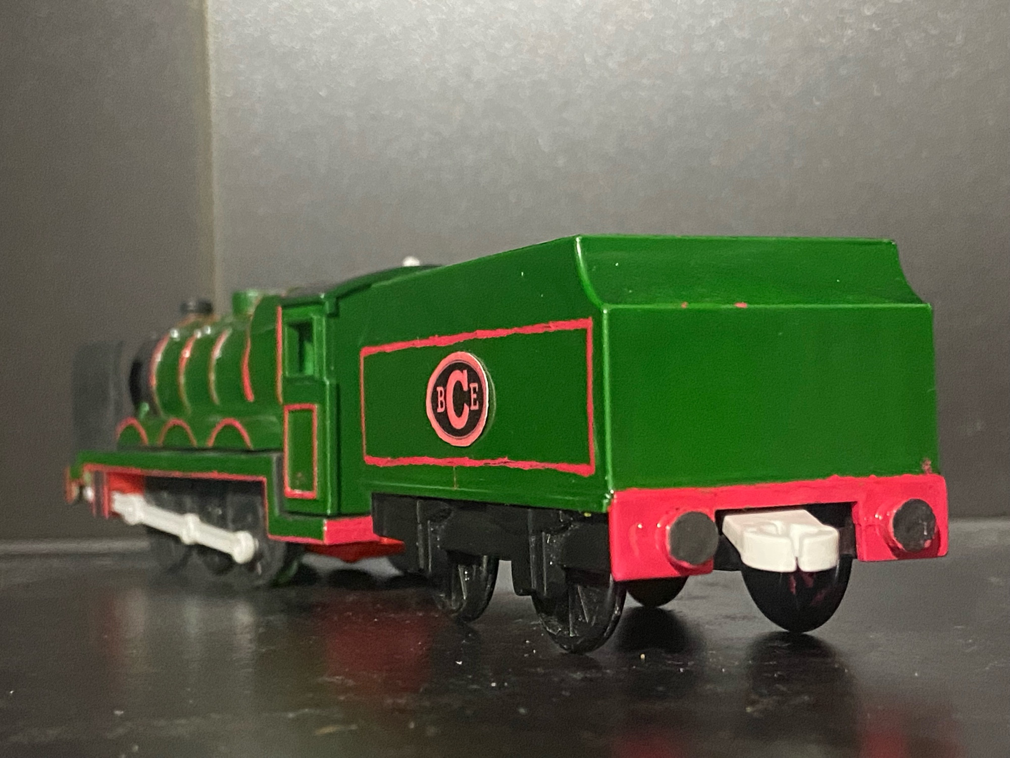 Side profile of the Big City Engine, he is painted dark green with red lining, there is a oval shape on his tender with the letters B C E written in Red Text, a direct rip from his Thomas Wooden Railway Toy.