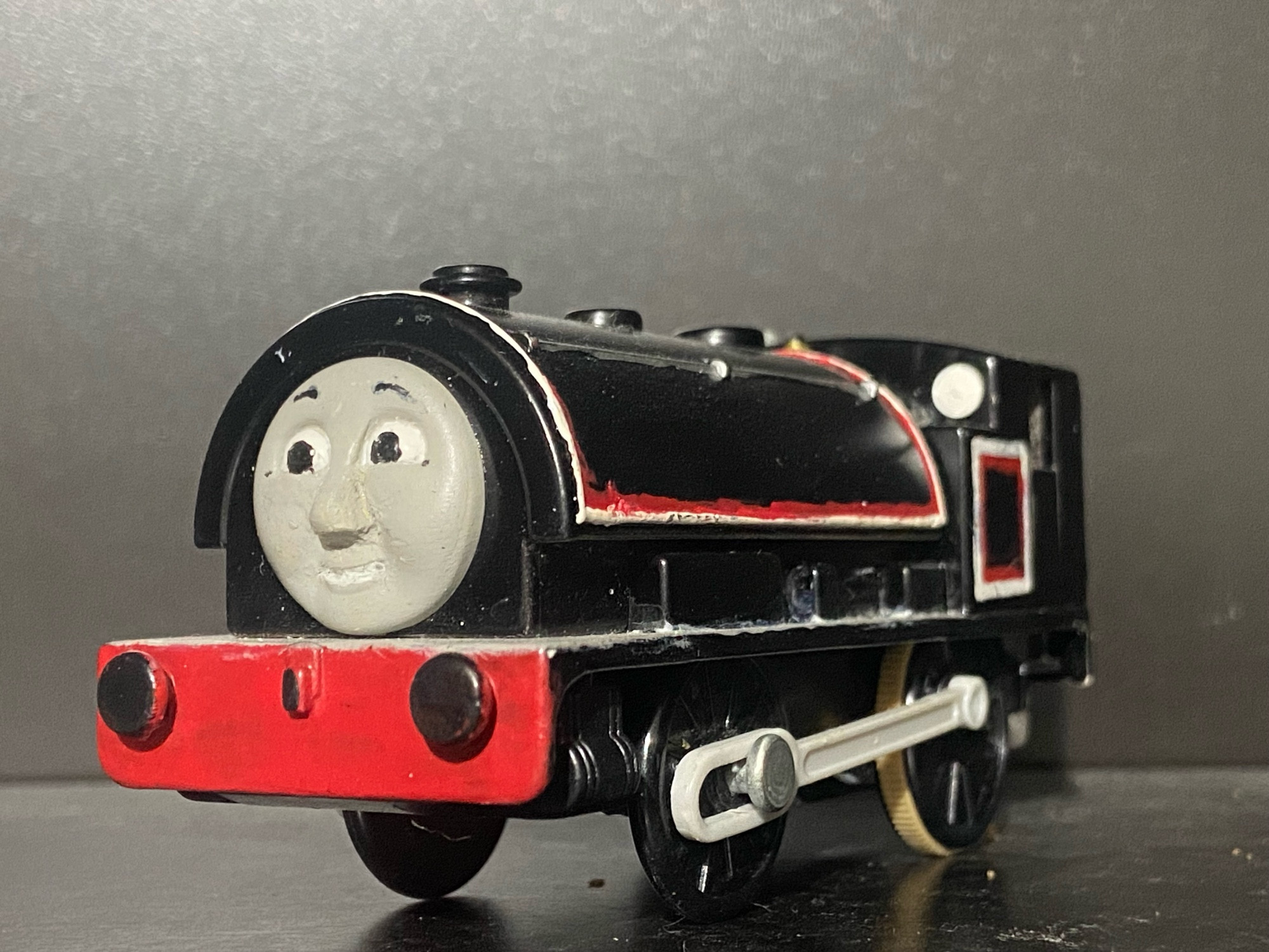 Side profile of Jinty, she has two tone white and red stripes across her saddle tank and bunker. There are white portholes on the front of her cab and she has a light grey footplate.