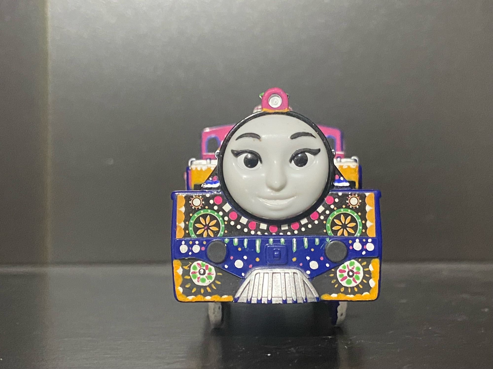 Front of Ashima from Thomas and Friends: The Great Race as a Plarail Toy.

She is painted in bright fuchsia with patterns in white, fuchsia, blue, orange, and green.