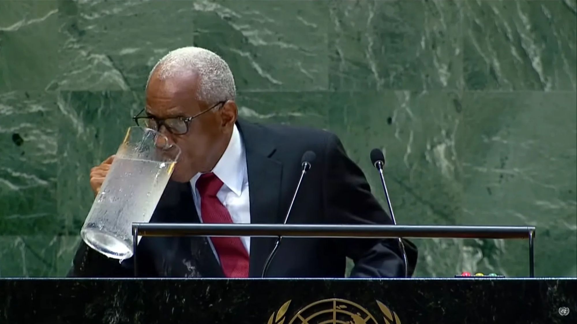 Haitian president Edgard Leblanc giving a speech at the UN and sipping from an enormous pitcher of water by picking it up one handed