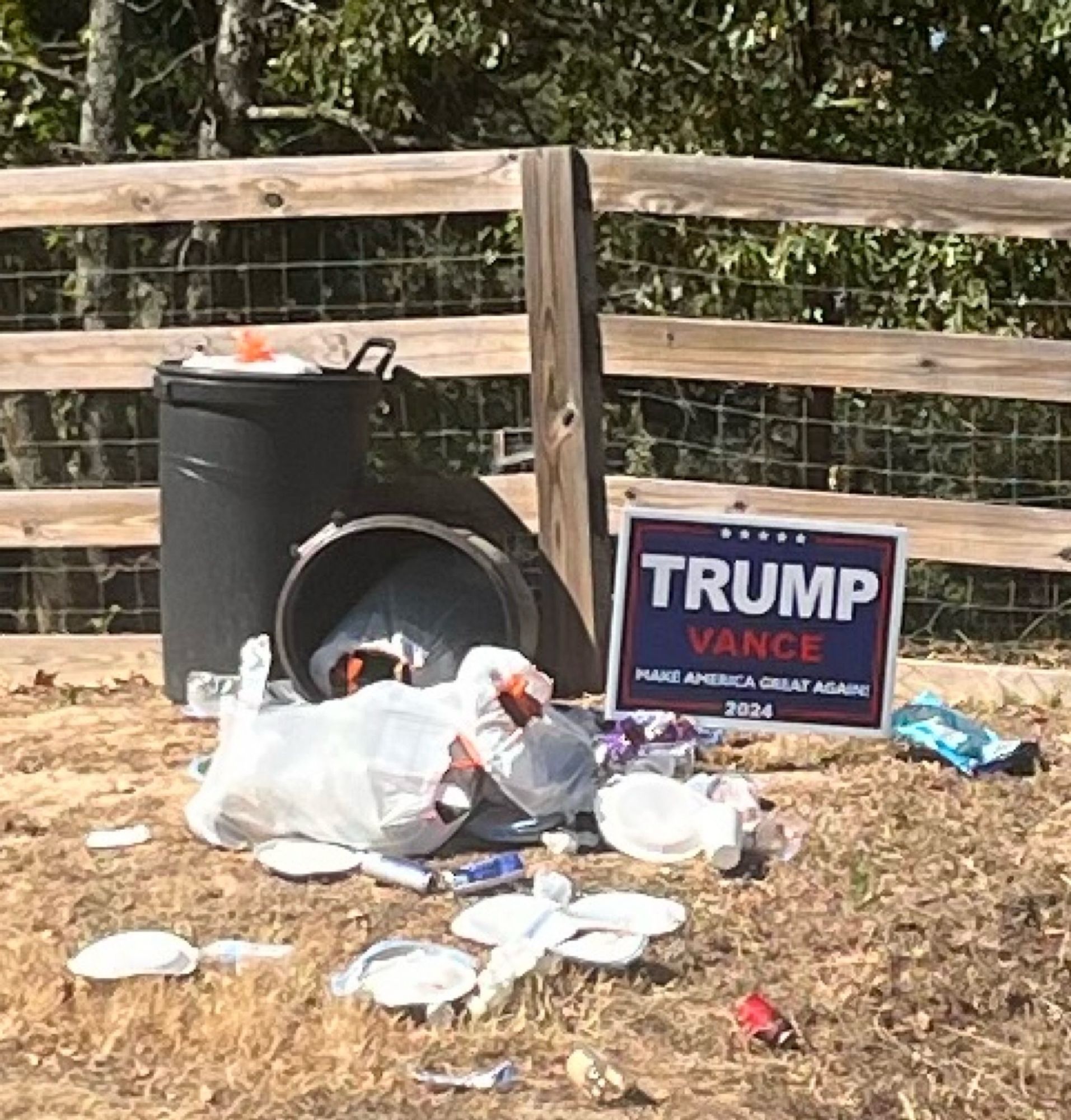 Ripped open trash bags in a driveway next to a Trump Vance sign