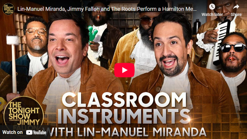 A youtube video of a clip from the Jimmy Fallon show, wherein Jimmy Fallon (L), Lin-Manuel Miranda (R), and The Roots, dressed in vaguely American Revolution-era clothing, play a medley of Hamilton songs on classroom instruments. 