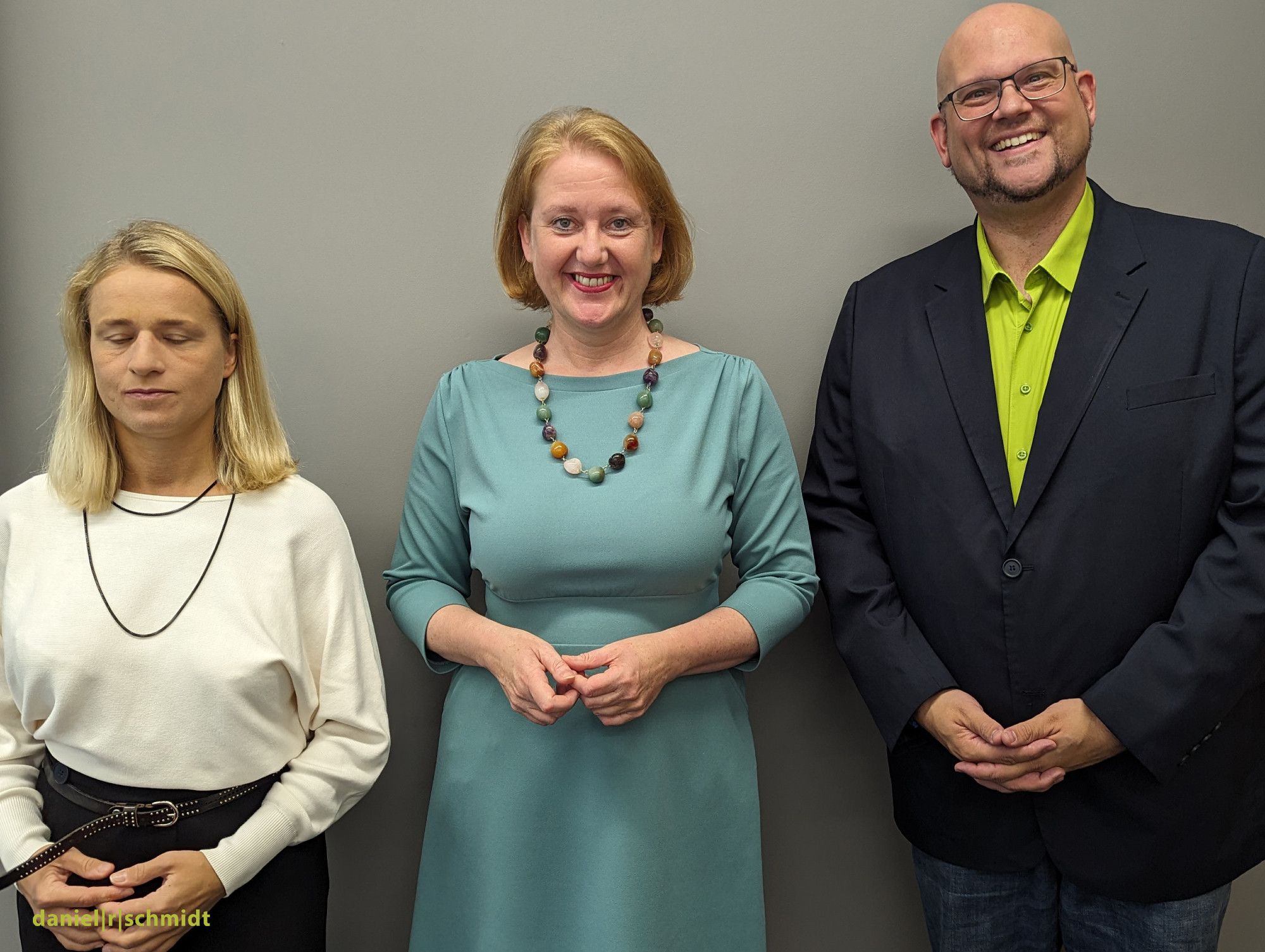 Vor einer grauen Wand stehen links DOSB-Vizepräsidentin Verena Bentele, in der Mitte Bundesministerin Lisa Paus und rechts Podcasthost Daniel R. Schmidt. Alle lächeln in die Kamera.