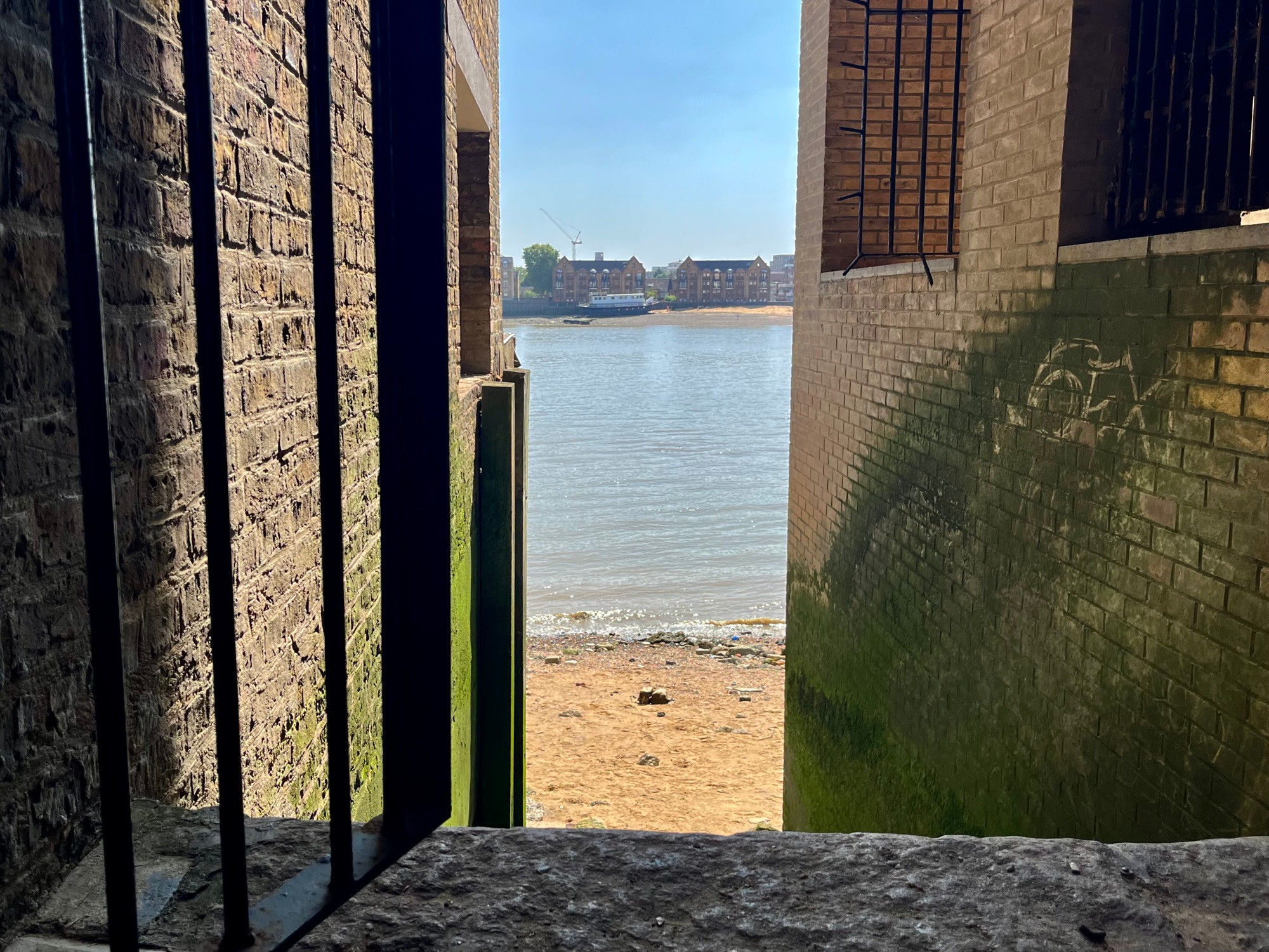 New Crane Stairs, Wapping, view from the top looking from a narrow alleyway across the river to Rotherhithe over the water on a gloriously sunny, blue sky day. 