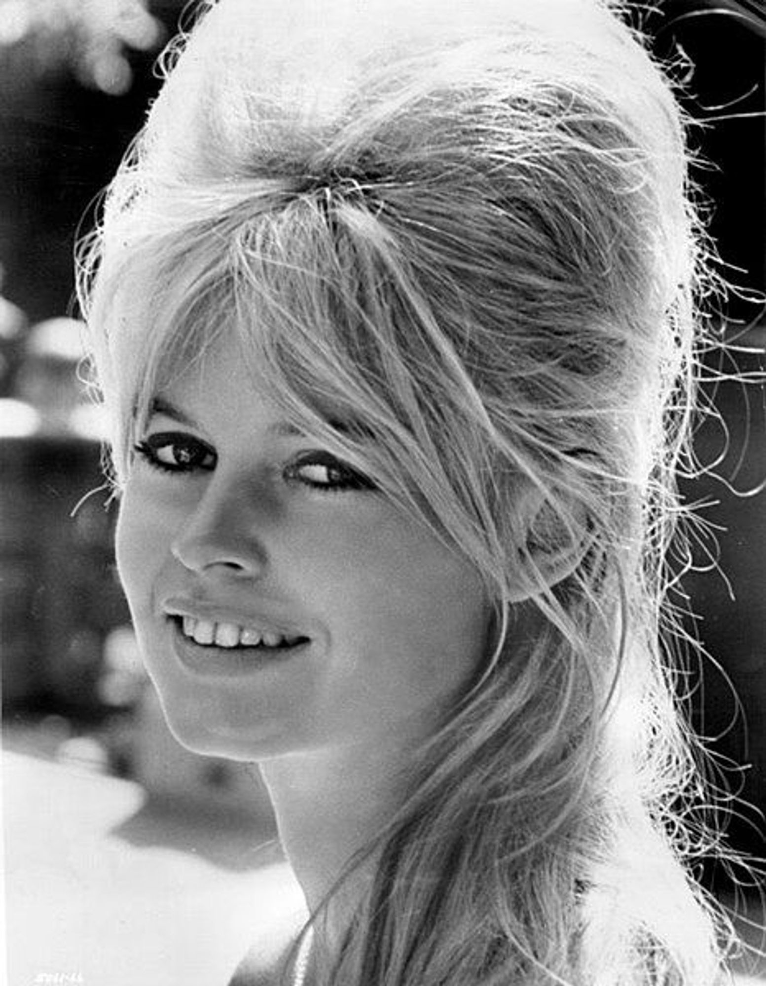 Photo en noir et blanc de Brigitte Bardot souriante, prise en 19621. Elle porte une coiffure volumineuse typique des années 60.