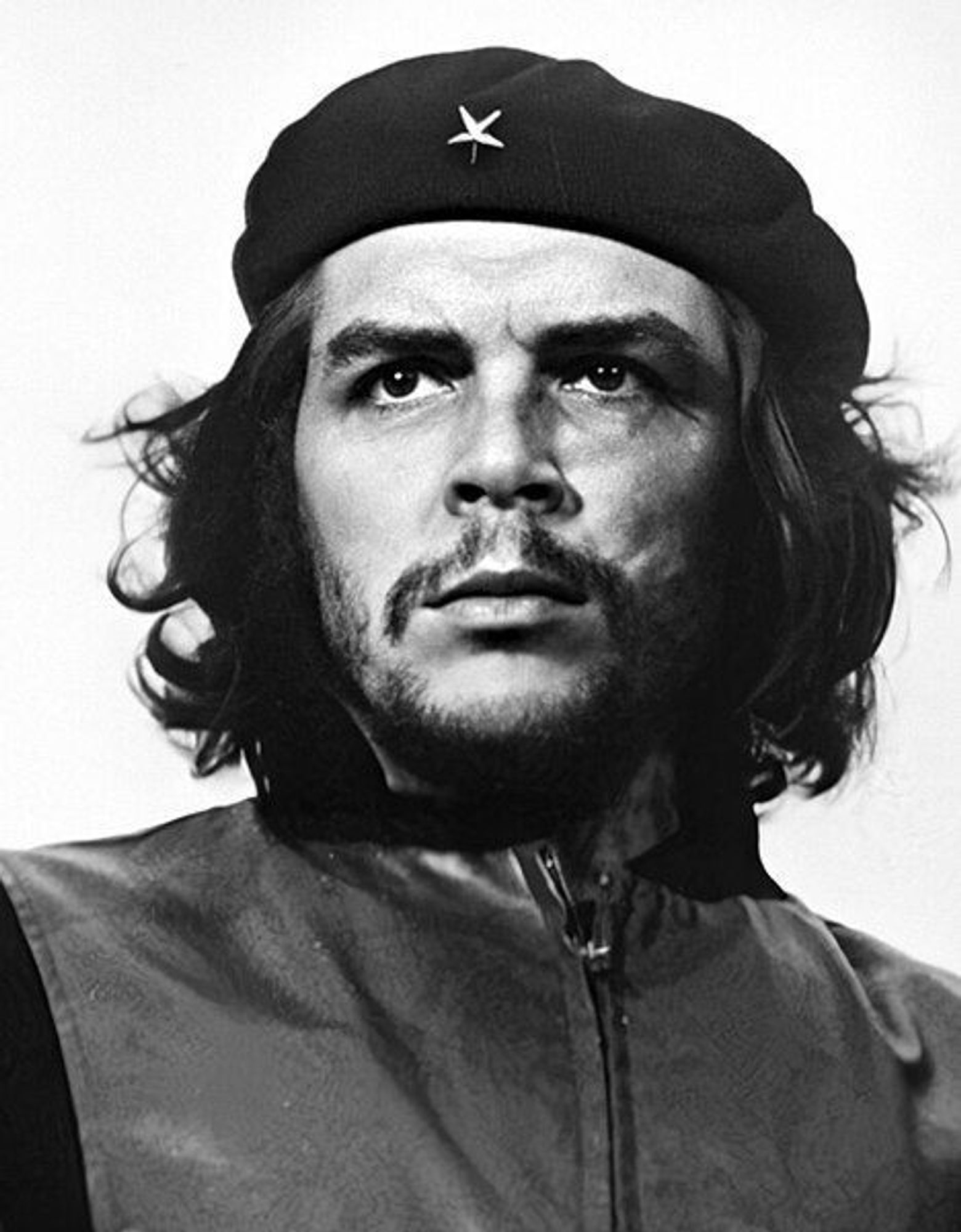 Photo en noir et blanc de Che Guevara, portant un béret avec une étoile brodée dessus, cheveux mis longs et moustache.